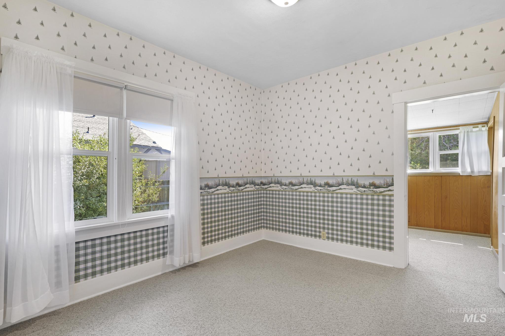 Spare room featuring wallpapered walls and baseboards