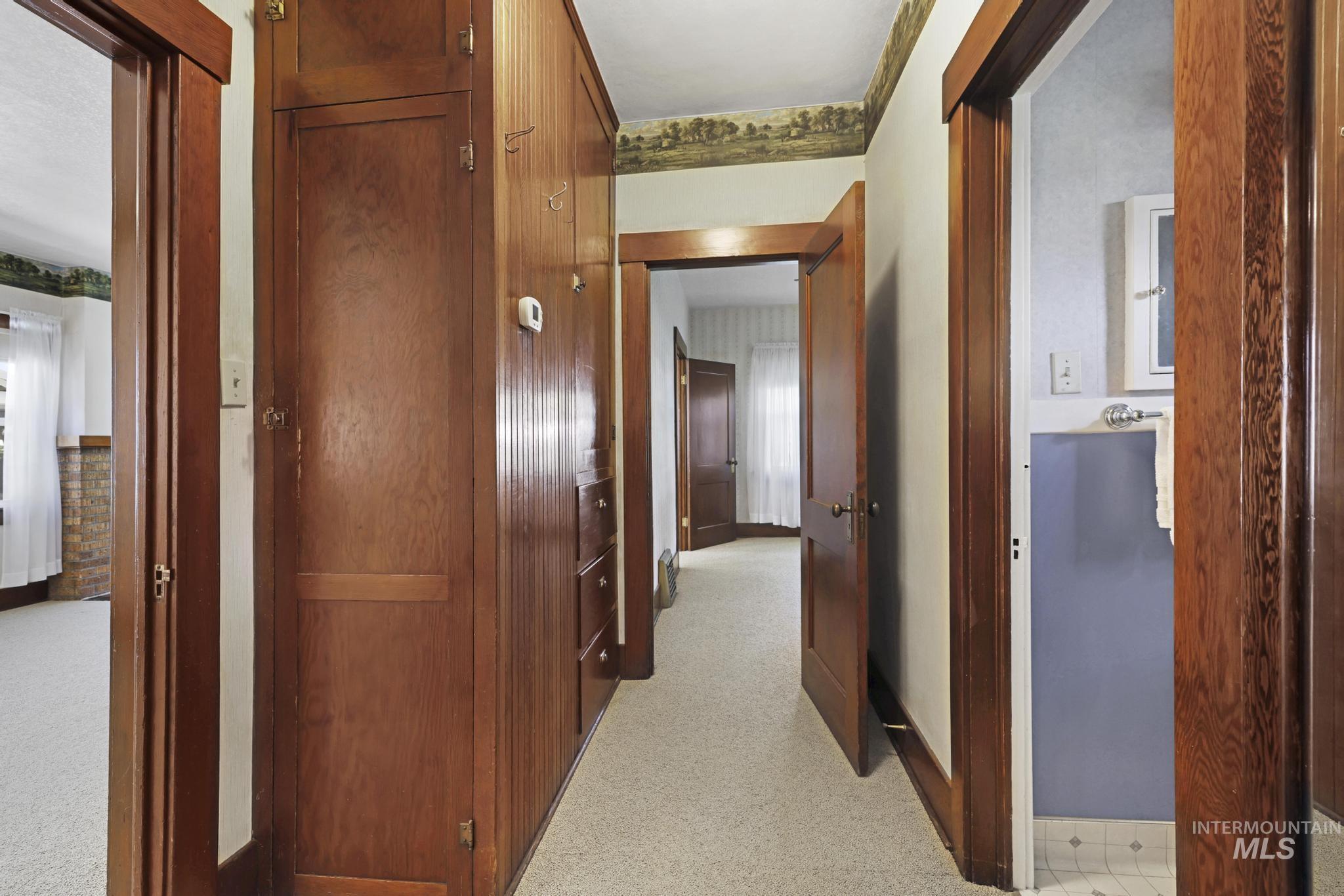 Hallway featuring light colored carpet and baseboards