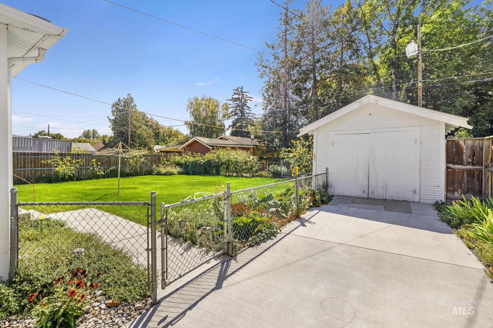 Fenced backyard featuring a gate, a storage unit, and a detached garage