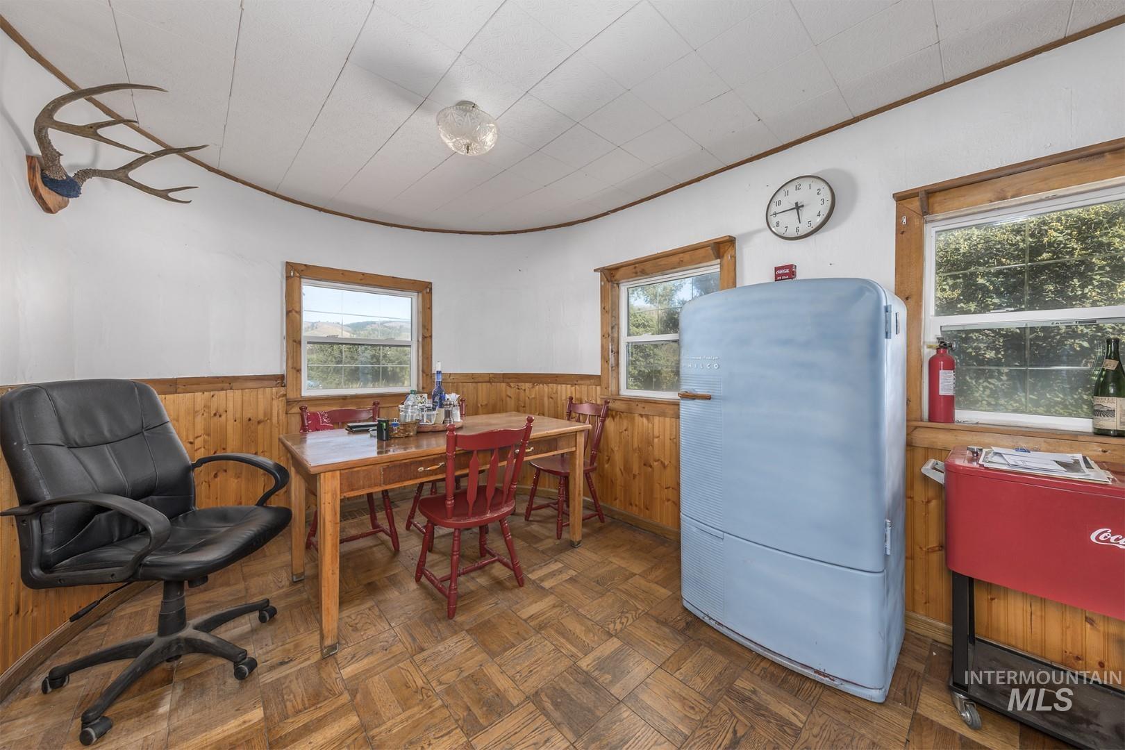 Dining space with wooden walls, a wainscoted wall, and ornamental molding