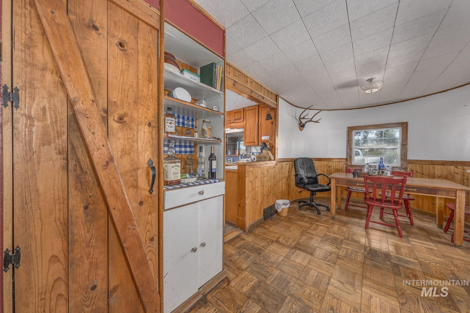 Kitchen featuring wood walls, wainscoting, brown cabinetry, and light countertops