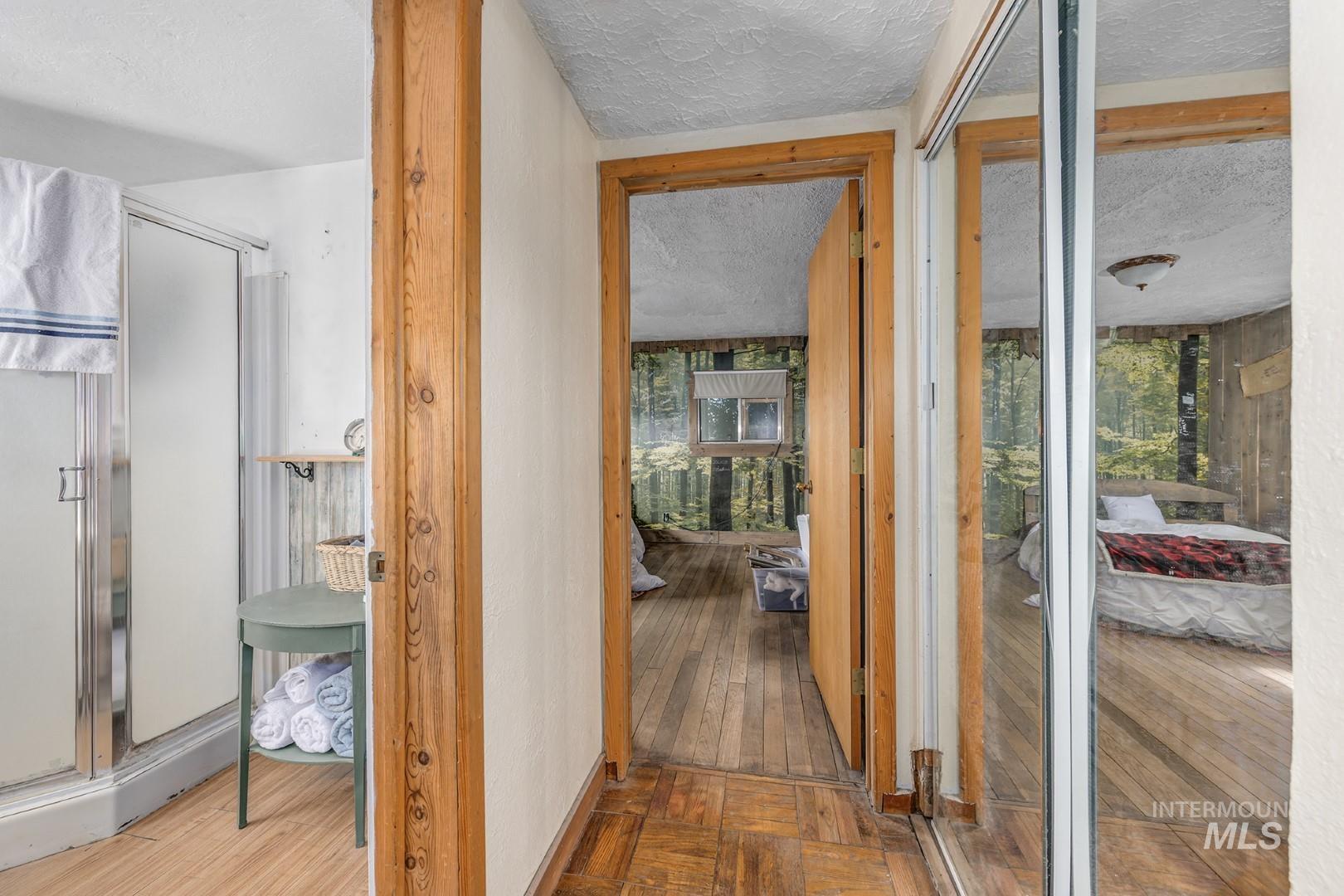 Corridor with a textured ceiling and hardwood / wood-style floors