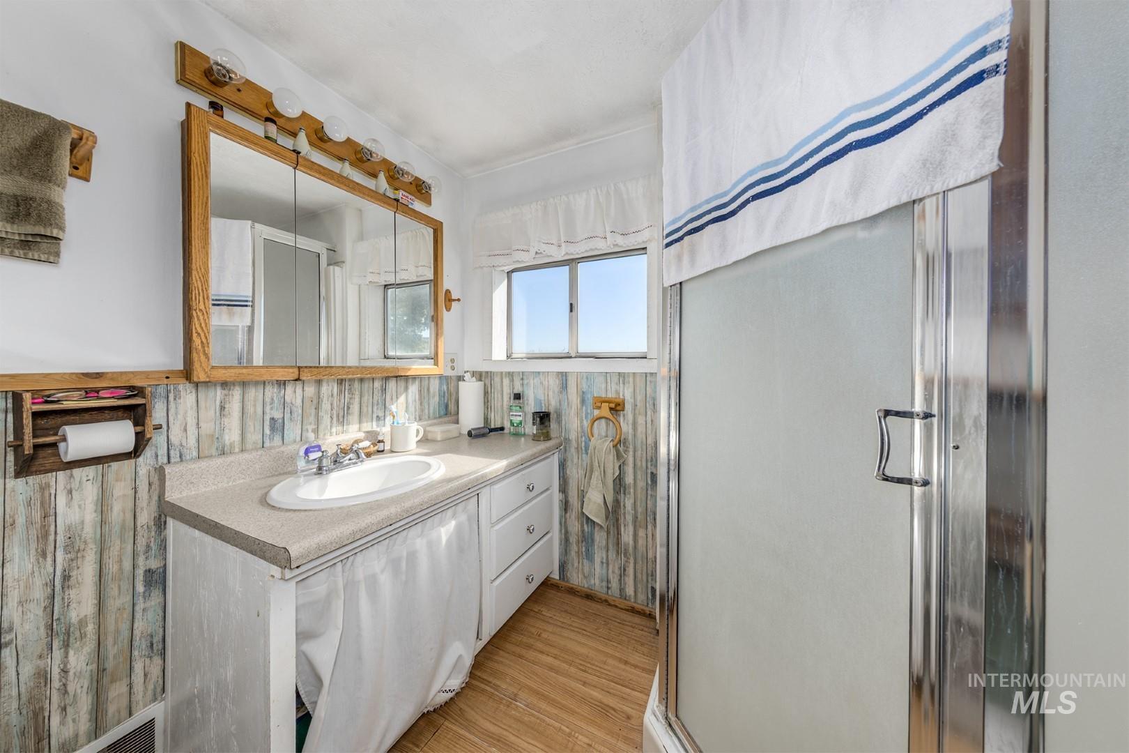 Bathroom featuring vanity, a shower stall, and light wood-style flooring