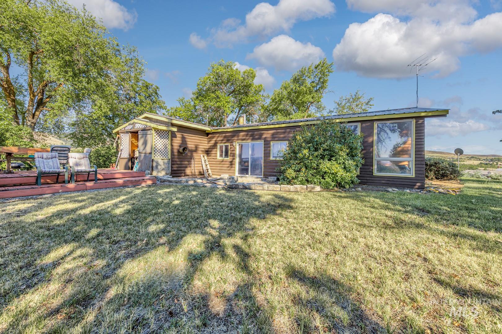 Back of house with a lawn, a wooden deck, and faux log siding
