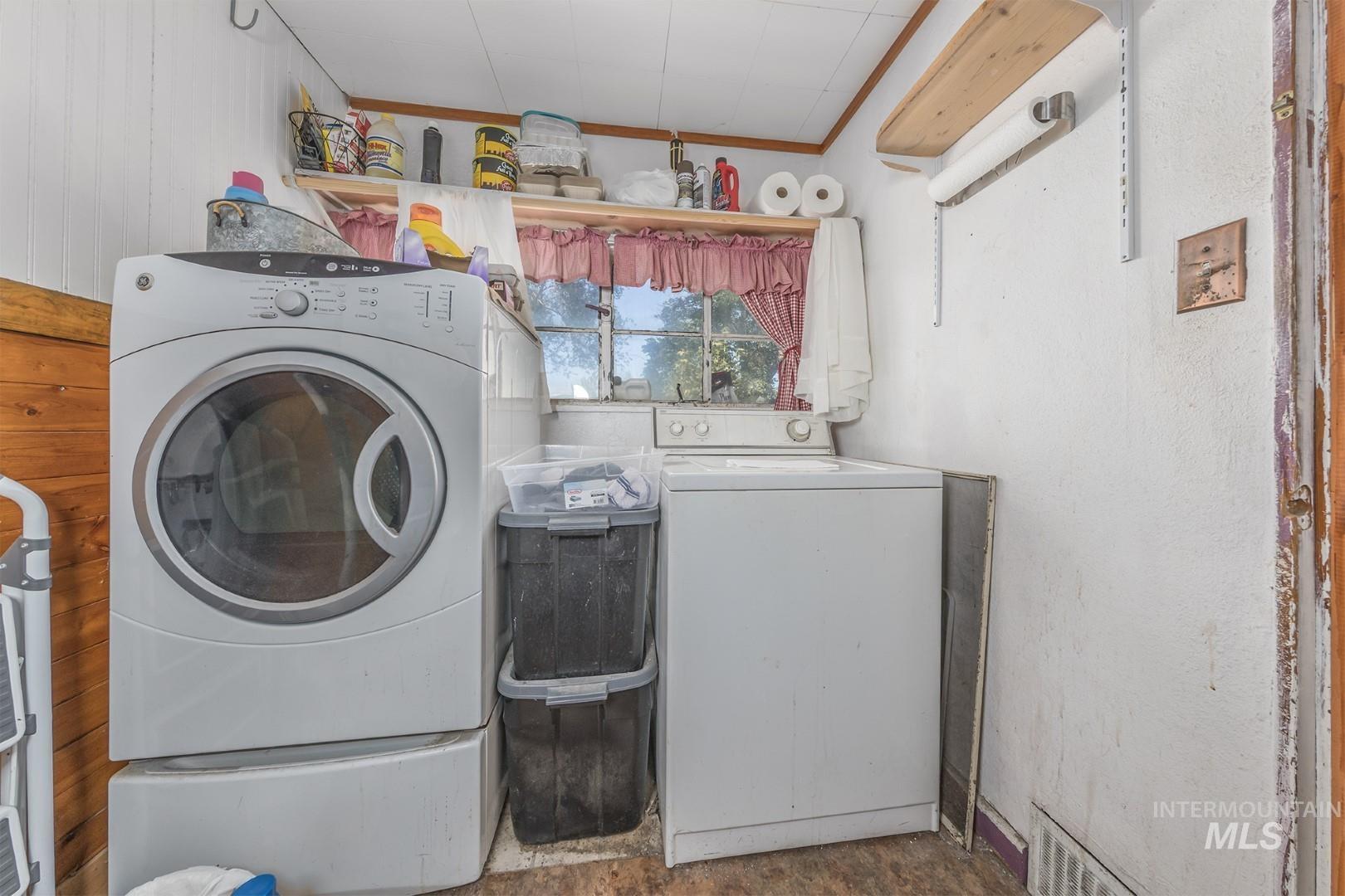 Washroom featuring washing machine and dryer and ornamental molding