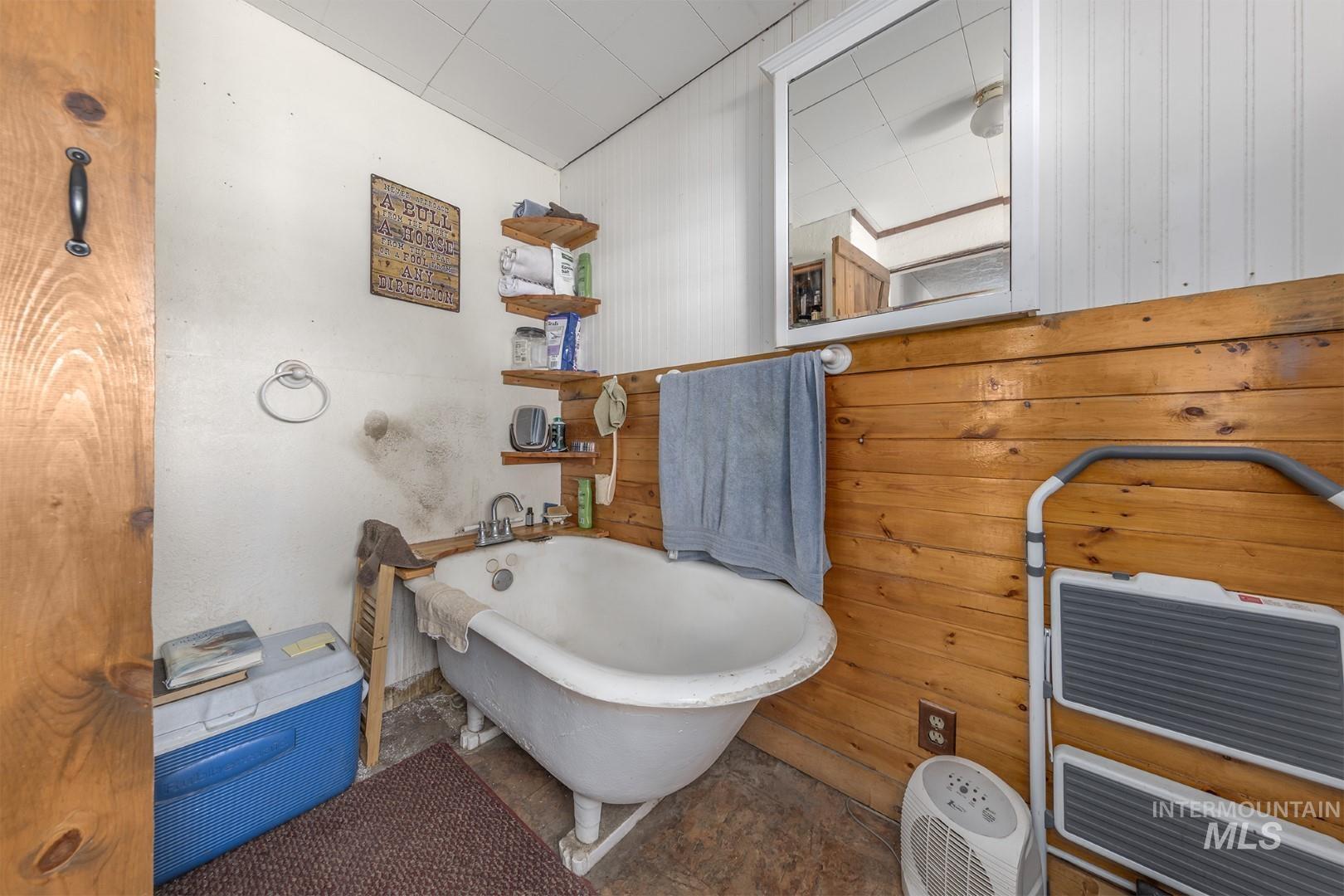 Full bathroom featuring wood walls and a freestanding tub