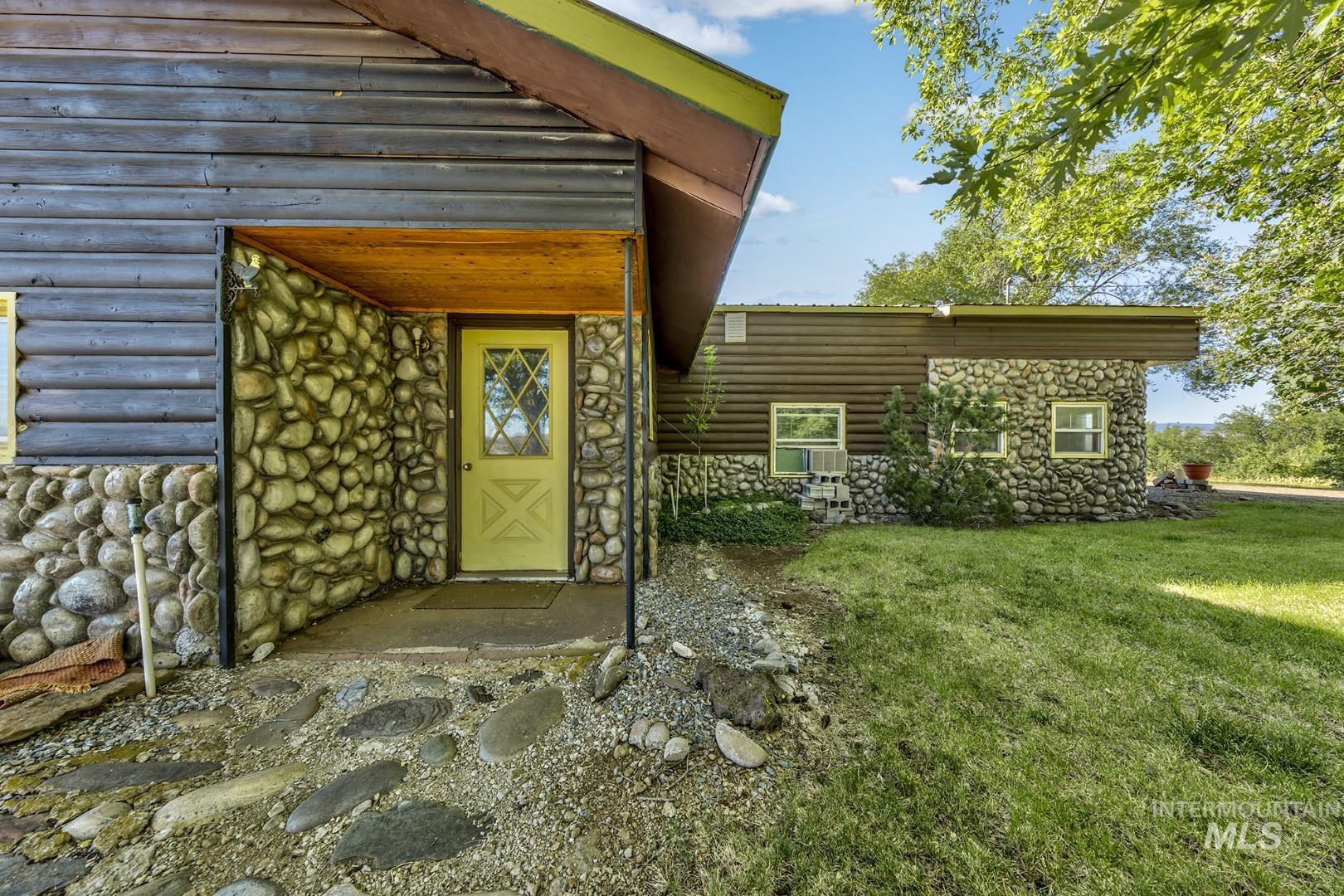 Doorway to property featuring stone siding and a lawn
