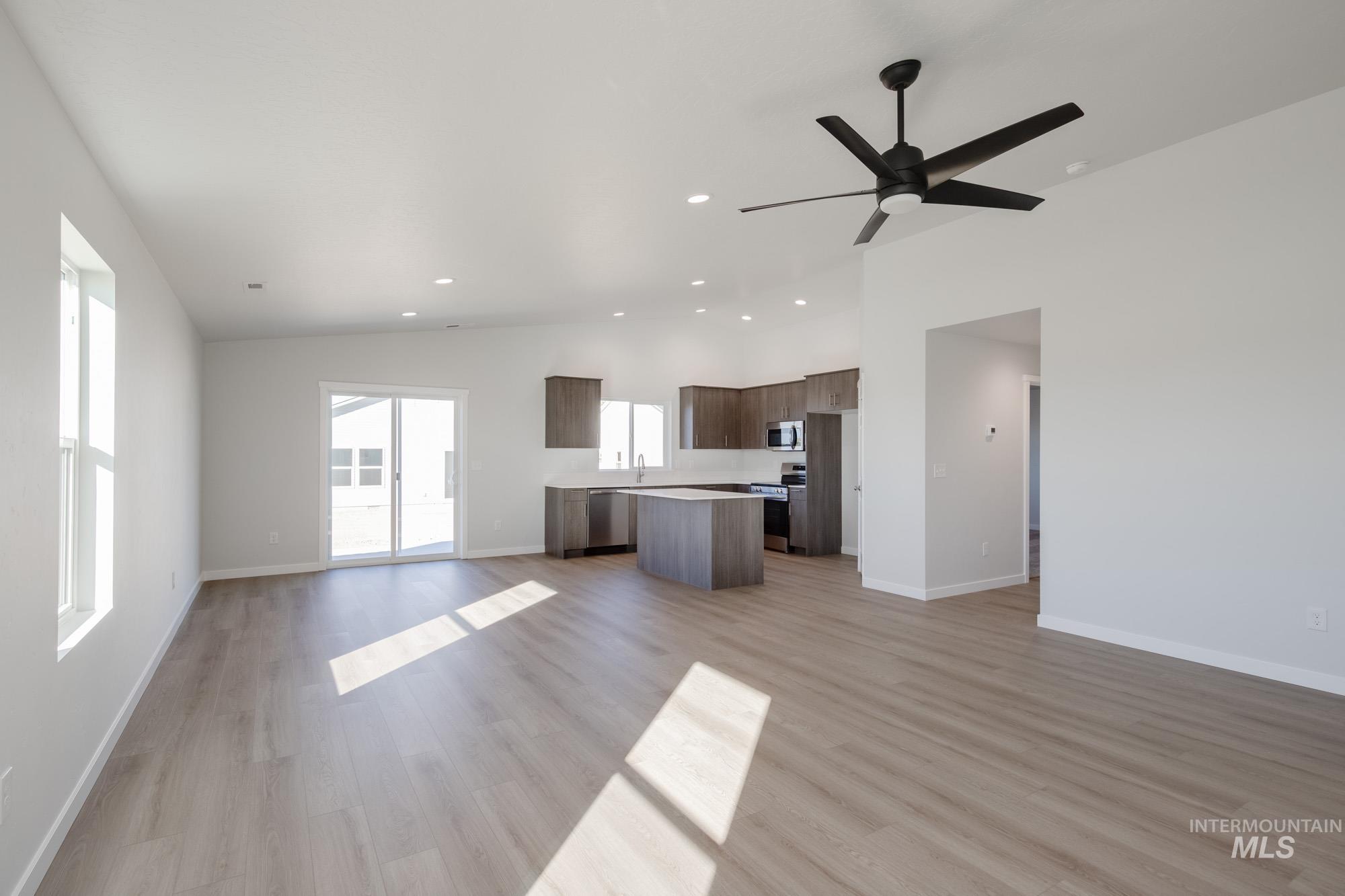Unfurnished living room featuring vaulted ceiling, light wood finished floors, recessed lighting, and ceiling fan