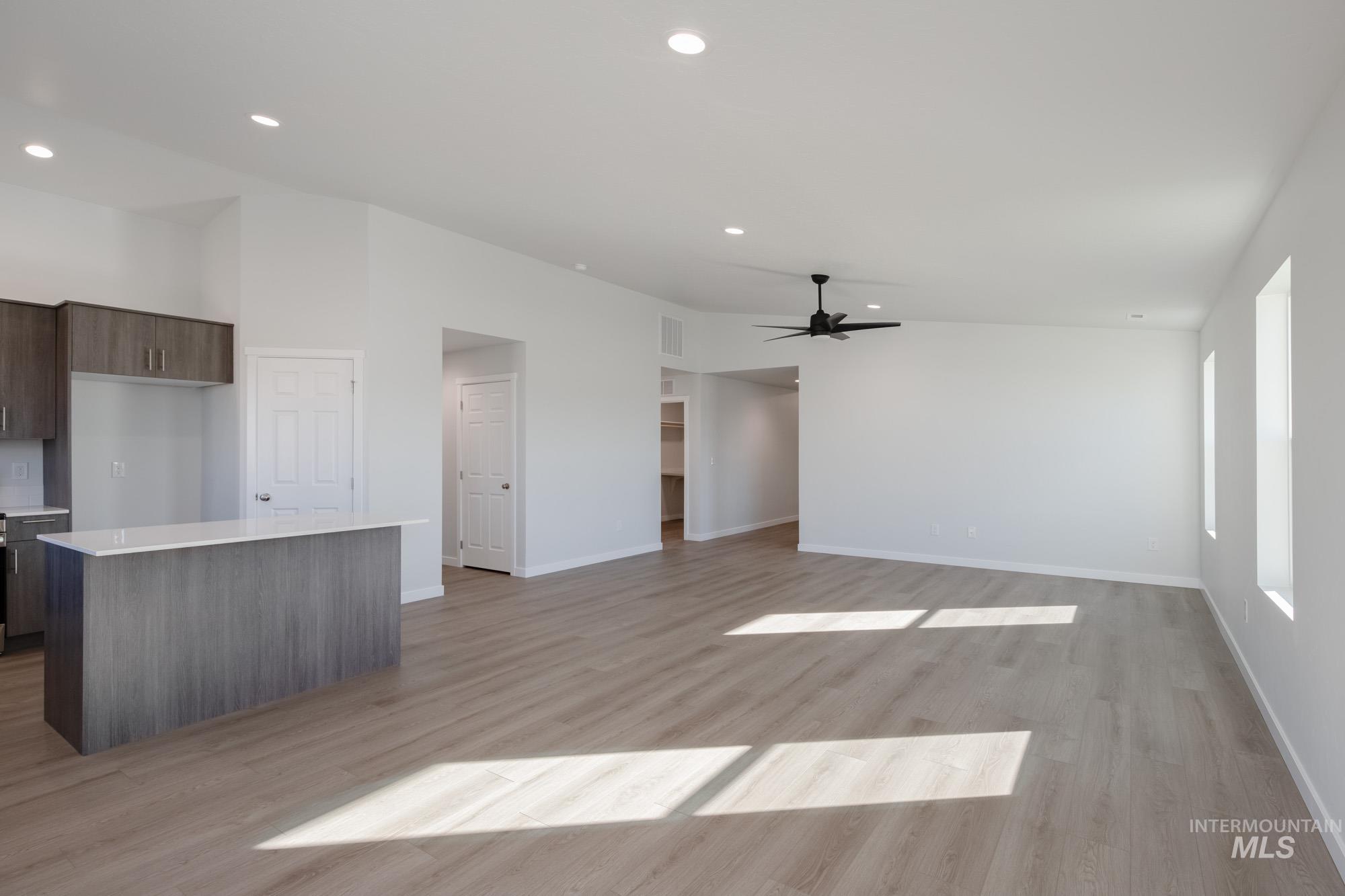 Unfurnished living room with recessed lighting, light wood-style floors, a ceiling fan, and vaulted ceiling
