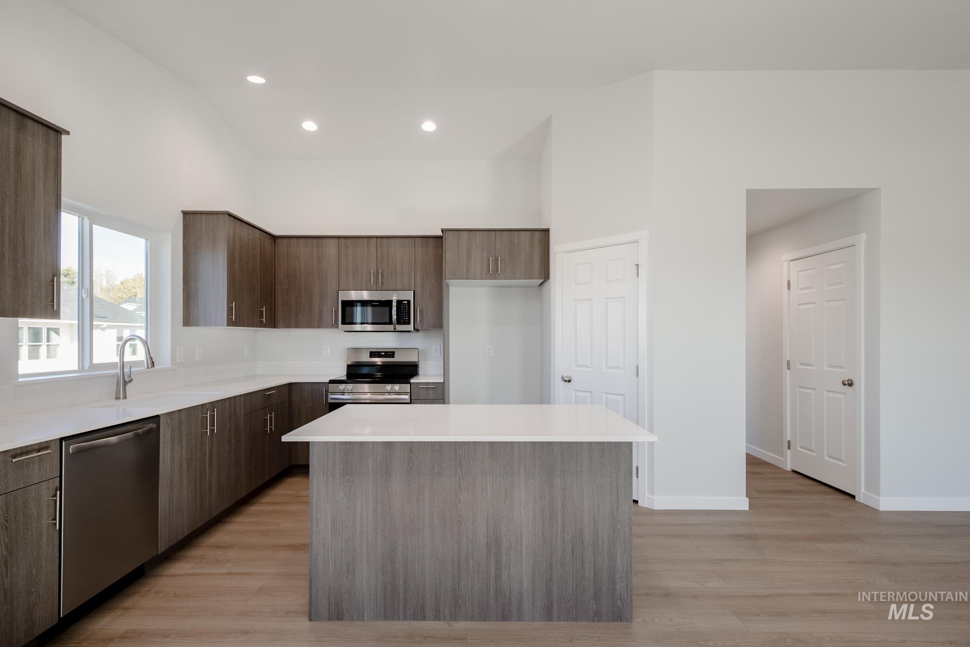 Kitchen with modern cabinets, stainless steel appliances, light wood-style floors, a kitchen island, and recessed lighting