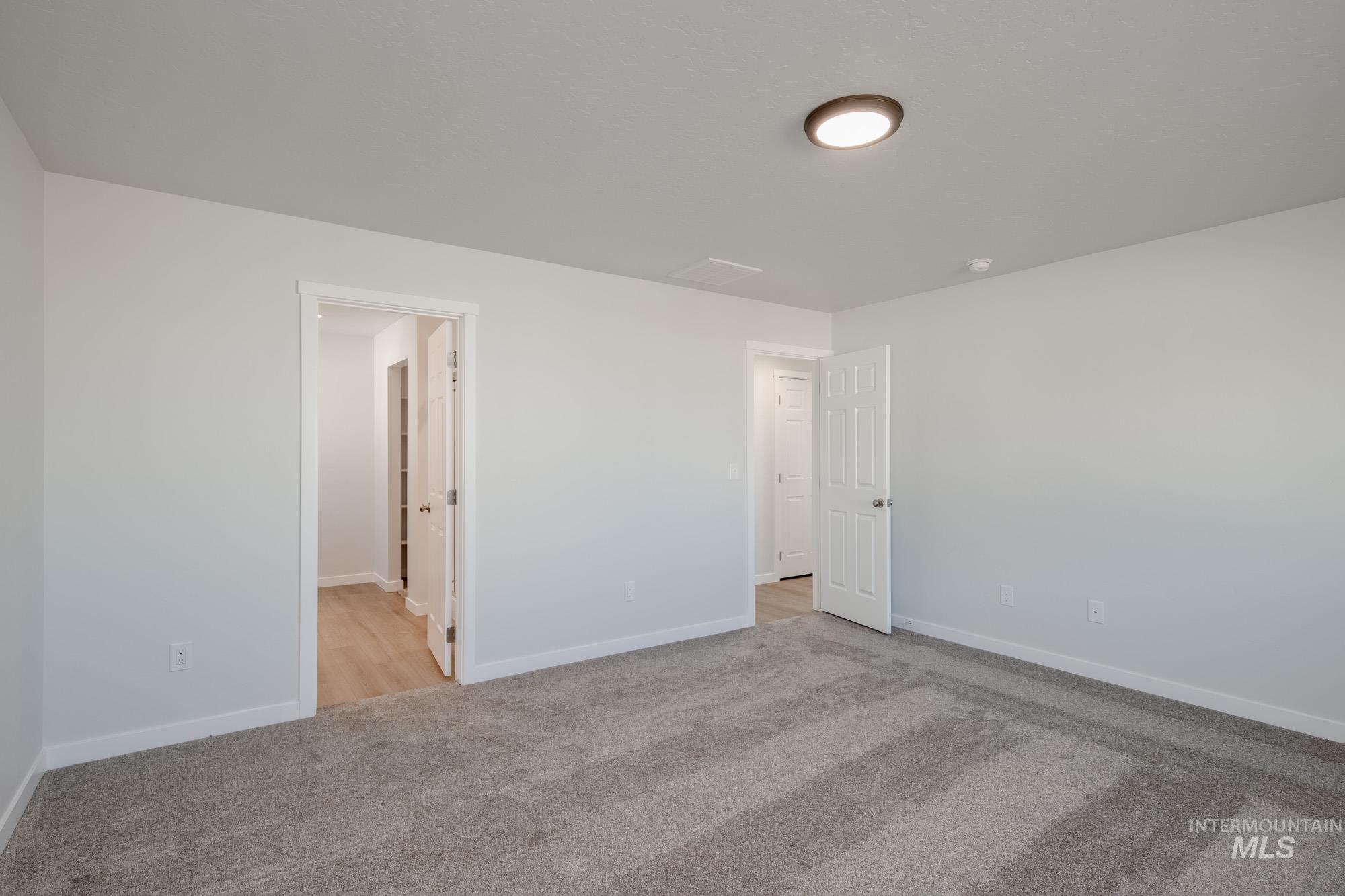 Unfurnished bedroom with light carpet and baseboards