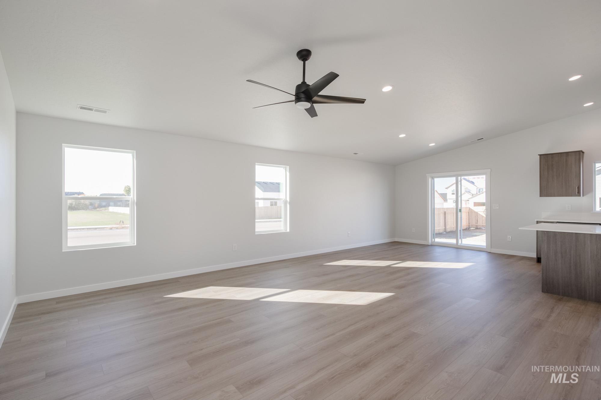Unfurnished living room featuring plenty of natural light, recessed lighting, light wood finished floors, and lofted ceiling