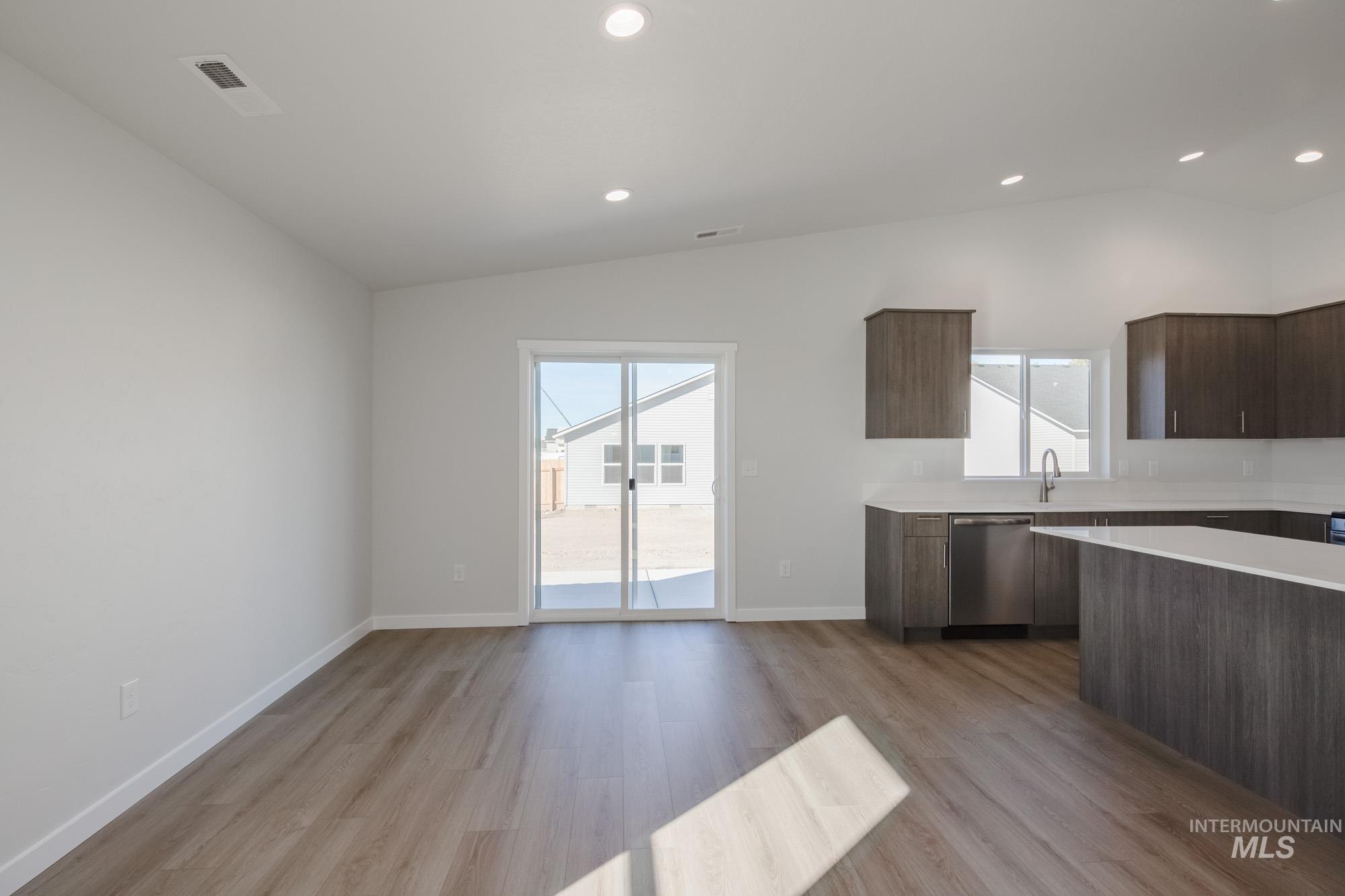 Kitchen featuring modern cabinets, lofted ceiling, dark brown cabinetry, plenty of natural light, and recessed lighting