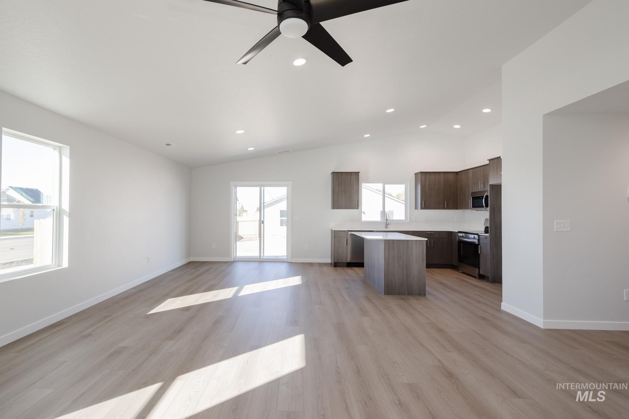 Kitchen featuring open floor plan, light countertops, a center island, light wood finished floors, and vaulted ceiling