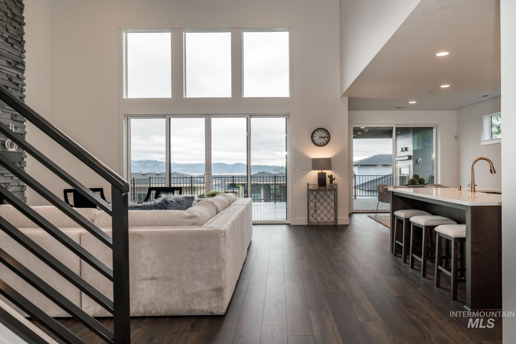 Living area featuring dark wood-type flooring, stairs, a mountain view, and a high ceiling