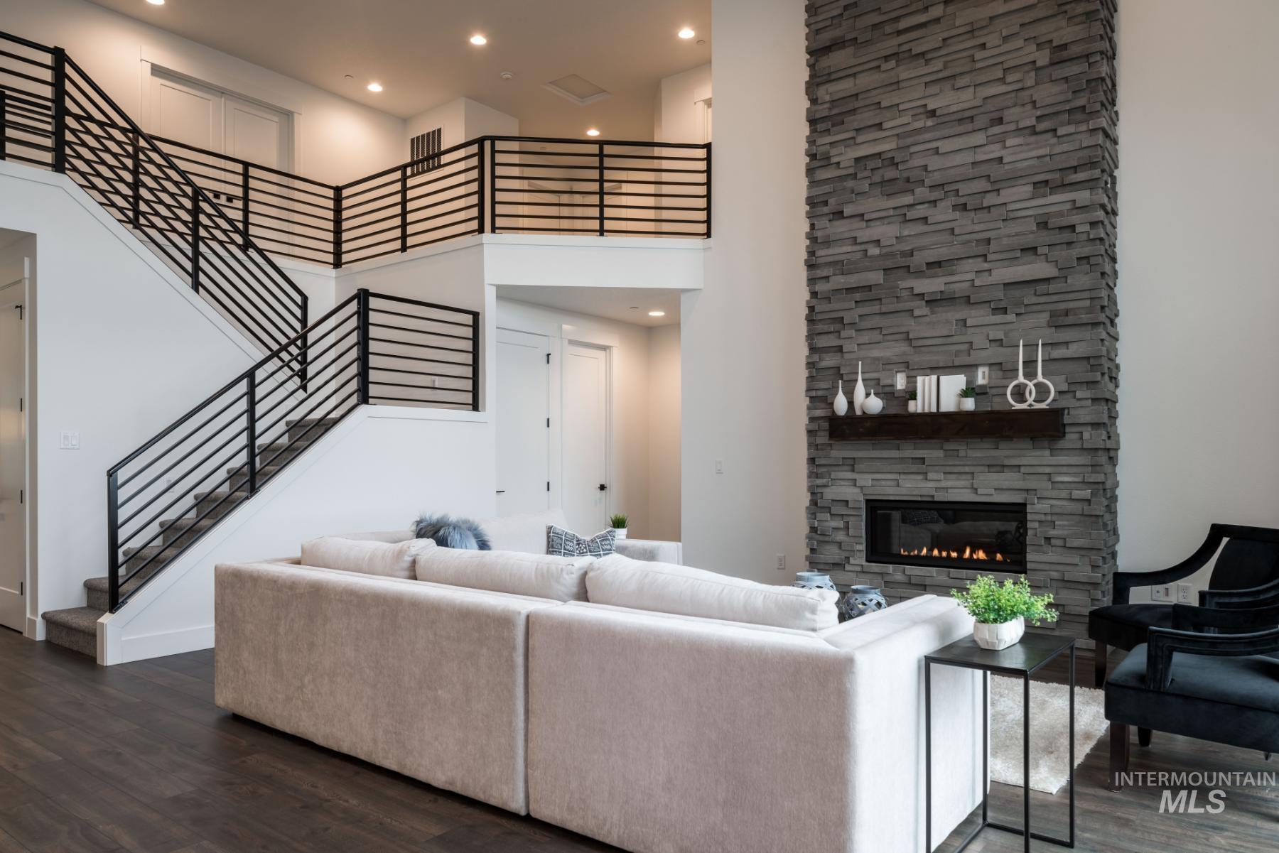 Living room featuring a high ceiling, dark wood-style floors, recessed lighting, a fireplace, and stairway