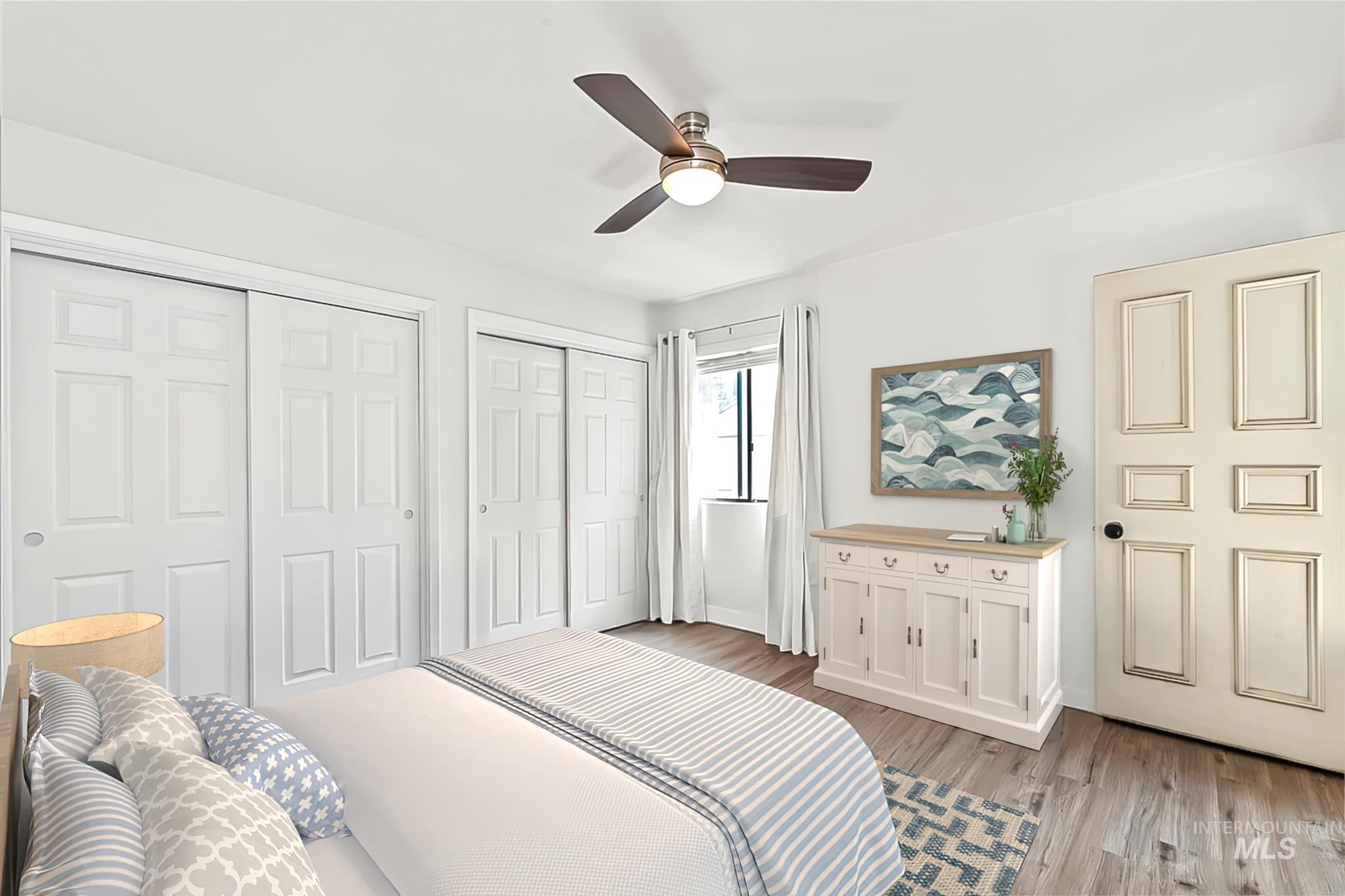 Bedroom with multiple closets, light wood-type flooring, and a ceiling fan
