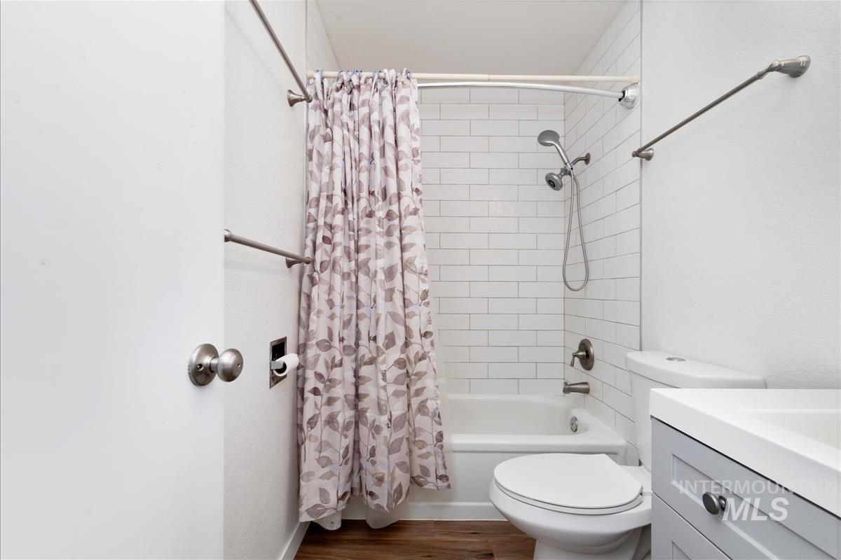 Bathroom featuring shower / bath combo, dark wood finished floors, and vanity