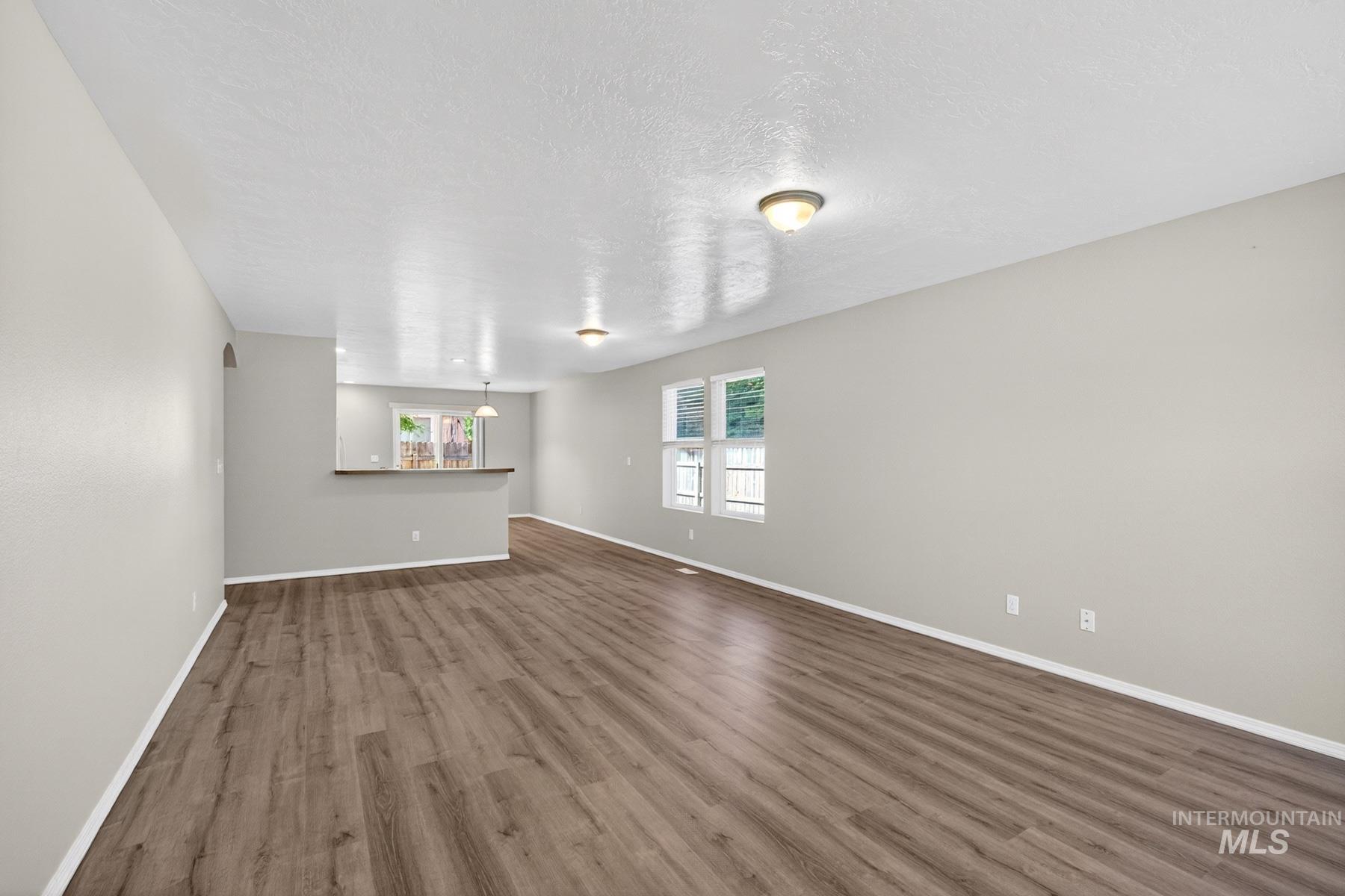 Spacious main living area featuring wood-finish flooring, neutral wall tones, and recessed ceiling lighting