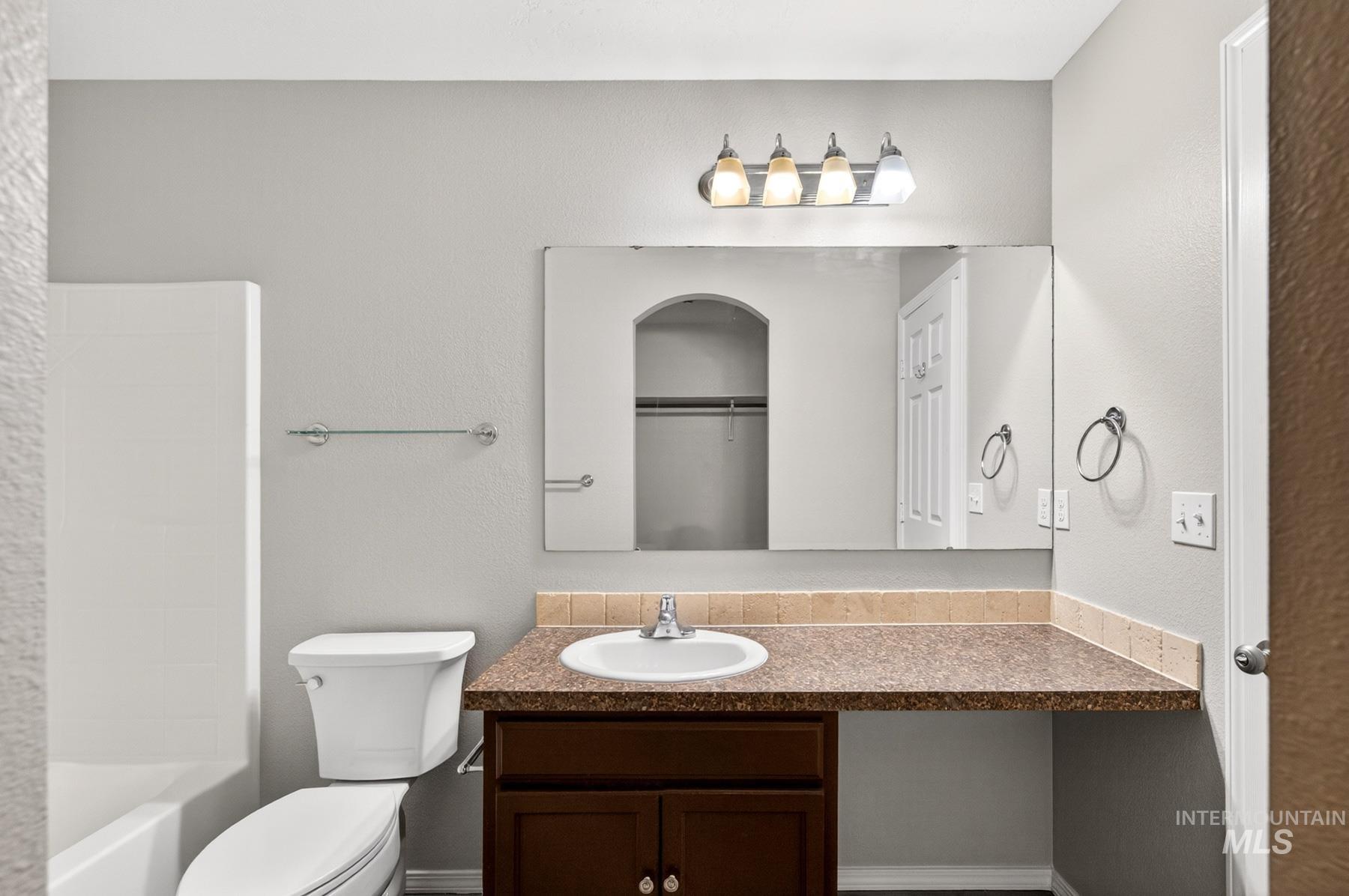 Bathroom vanity featuring an integrated sink, a dark wood-finish cabinet, and a large wall-mounted mirror