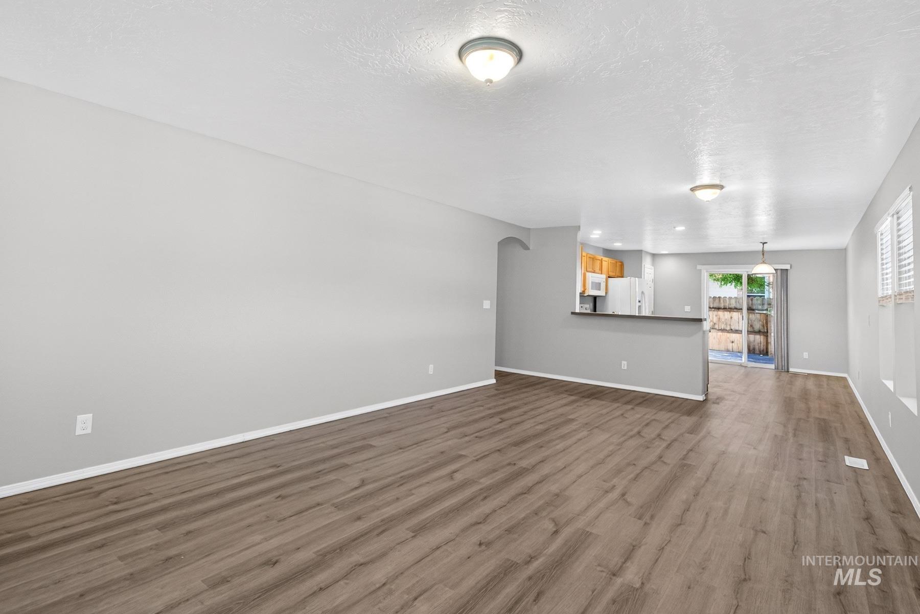 Spacious main living area featuring wood-finish flooring, neutral gray walls, and white trim
