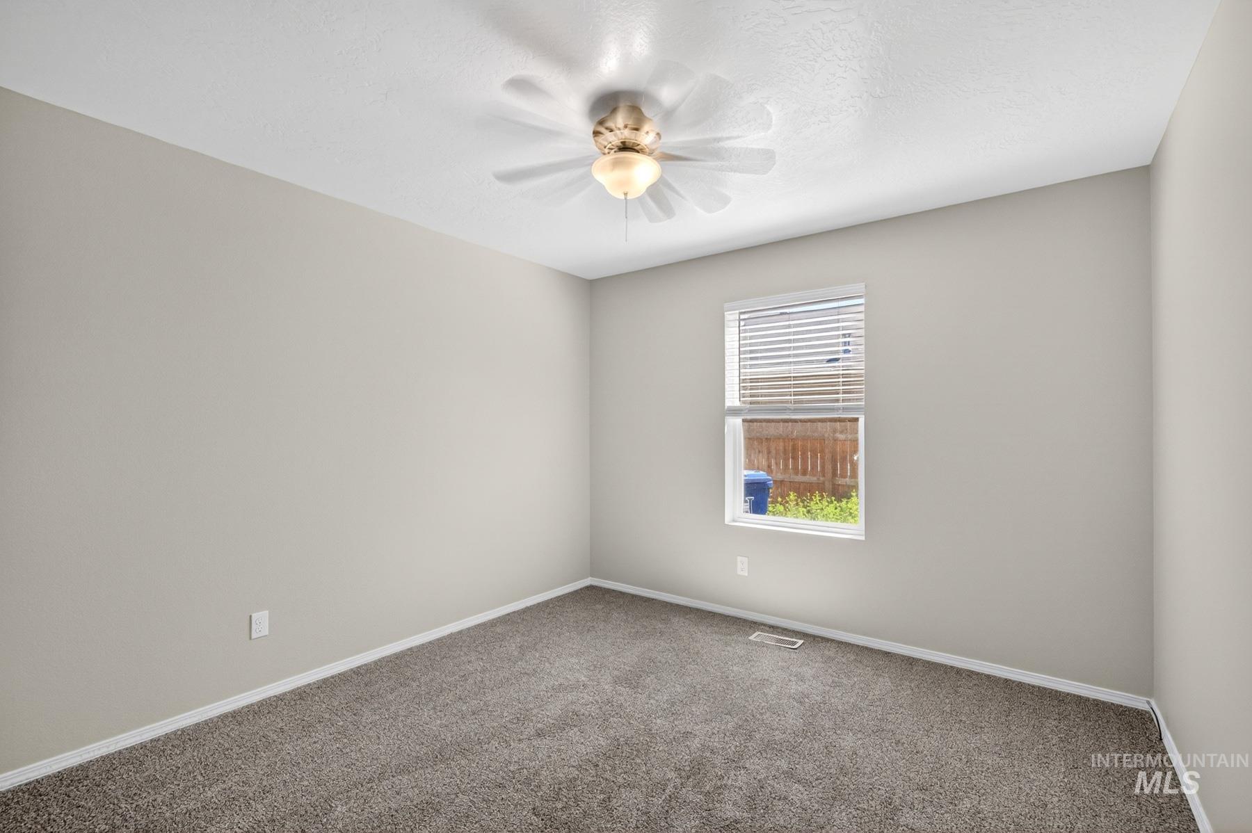 Carpeted room featuring a single window with horizontal blinds, a ceiling fan with integrated lighting, light-toned wall paint, and white baseboards