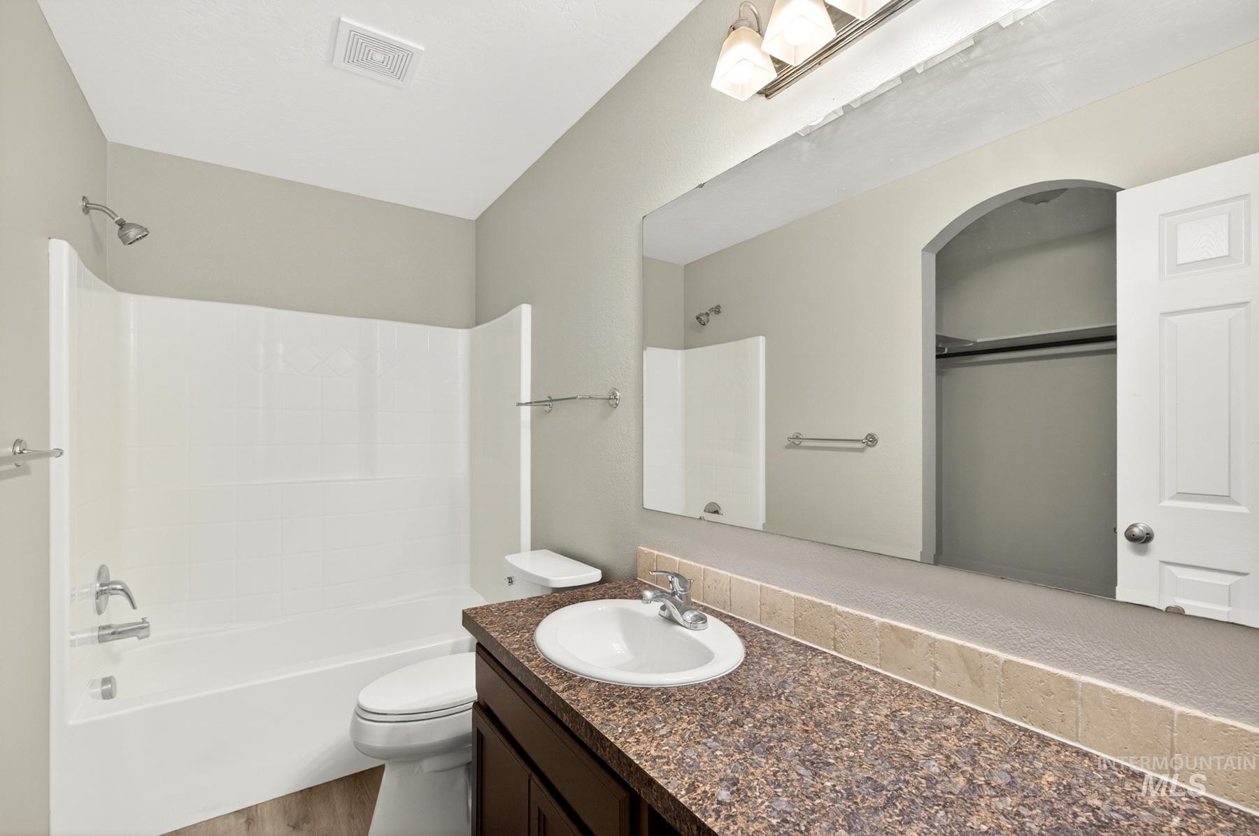 Bathroom featuring a white bathtub with integrated shower, a white toilet, and a vanity with a circular sink