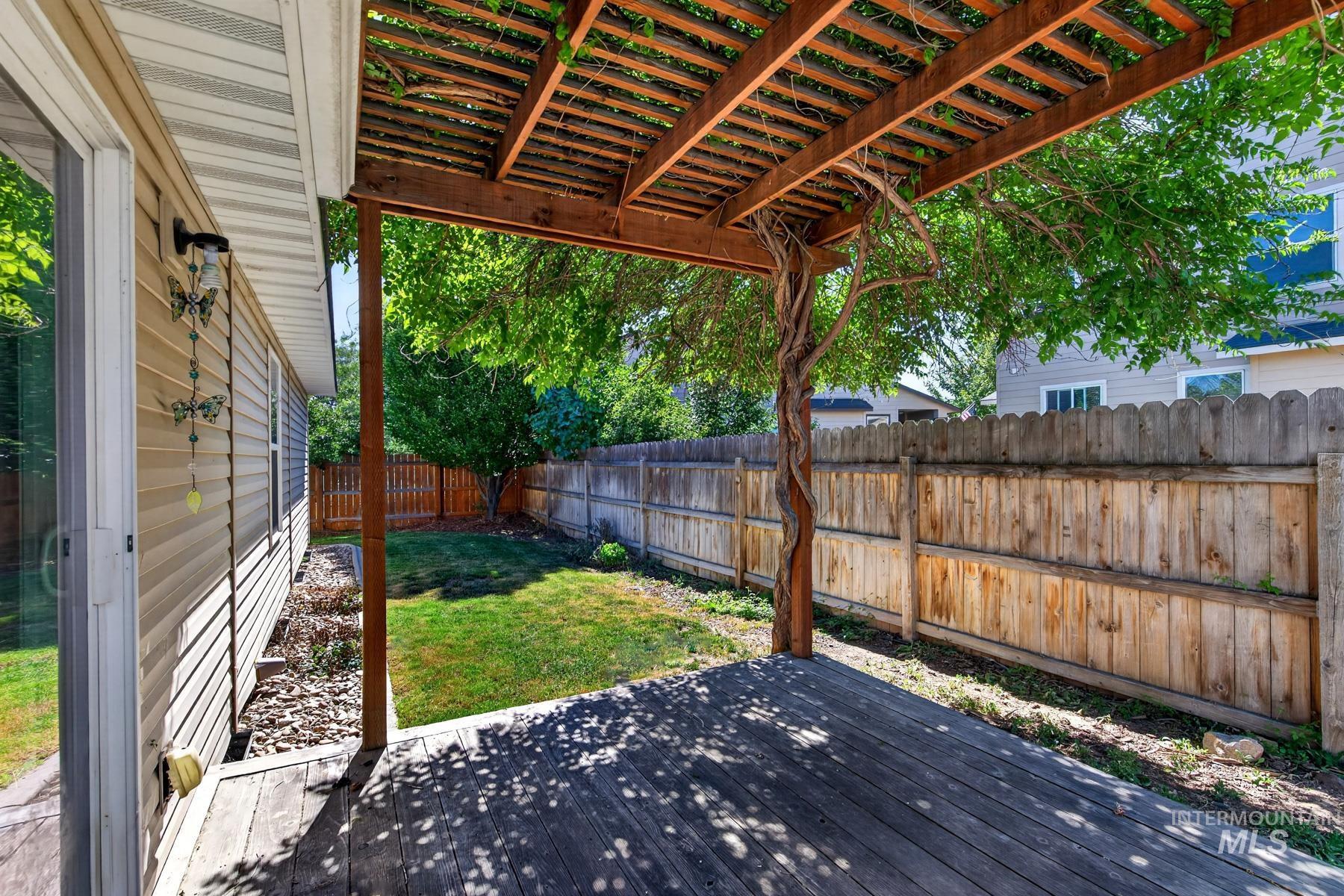 Expansive wood-finish deck with a pergola, bordered by a privacy fence