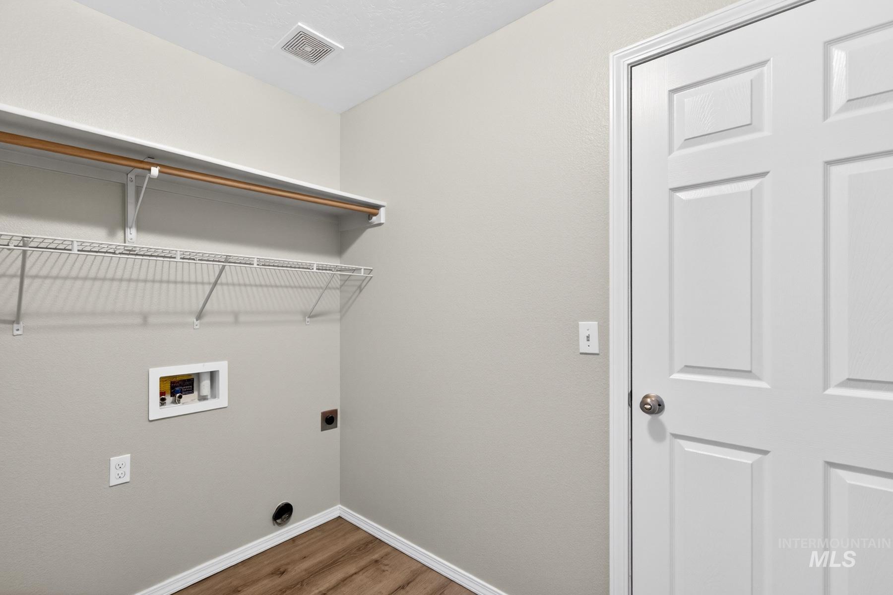 Dedicated laundry area featuring wire shelving, a wooden hanging rod, utility hookups, and wood-finish flooring