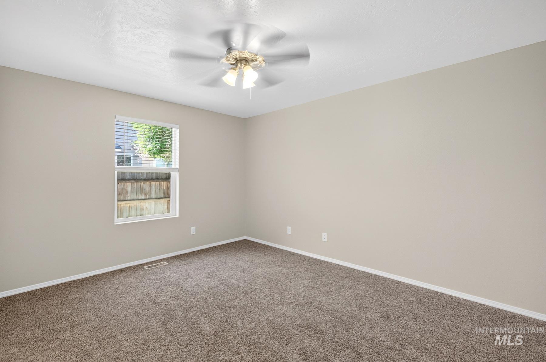 Carpeted room featuring a ceiling fan with integrated lighting, a double-hung window with blinds, and neutral wall paint