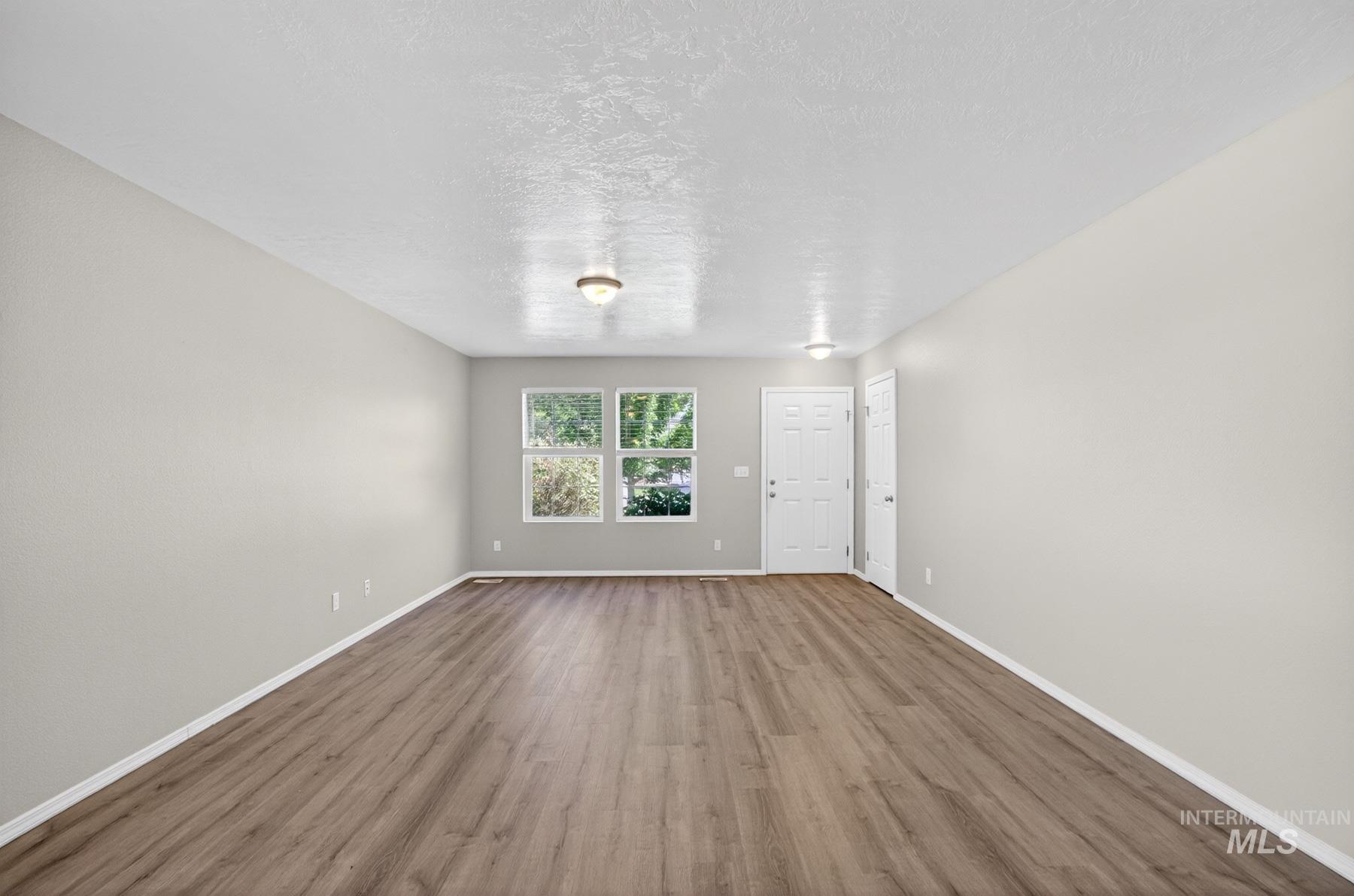 Bright living space featuring wood-finish flooring, light gray wall paint, white baseboards, and a white ceiling