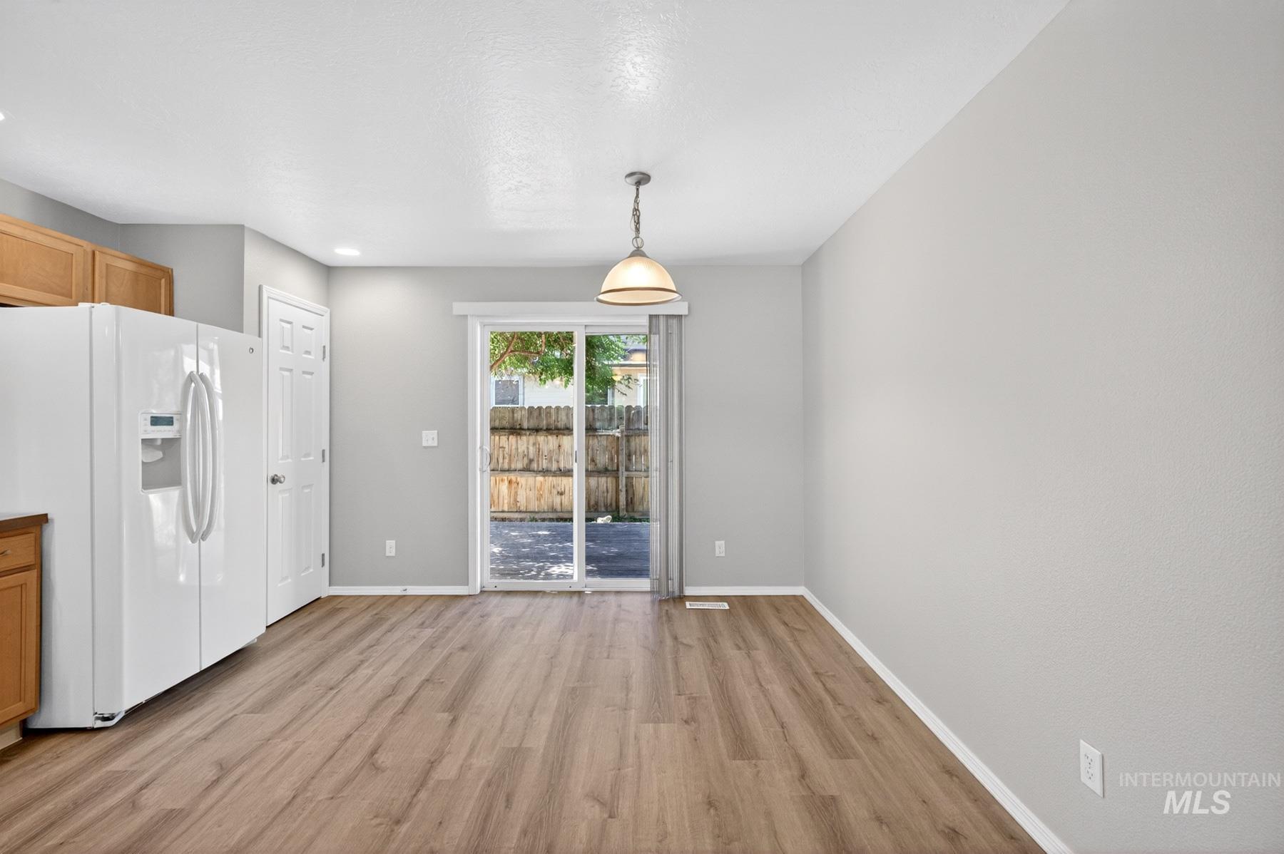 Dining area featuring wood-finish flooring, recessed lighting, and a contemporary pendant light fixture