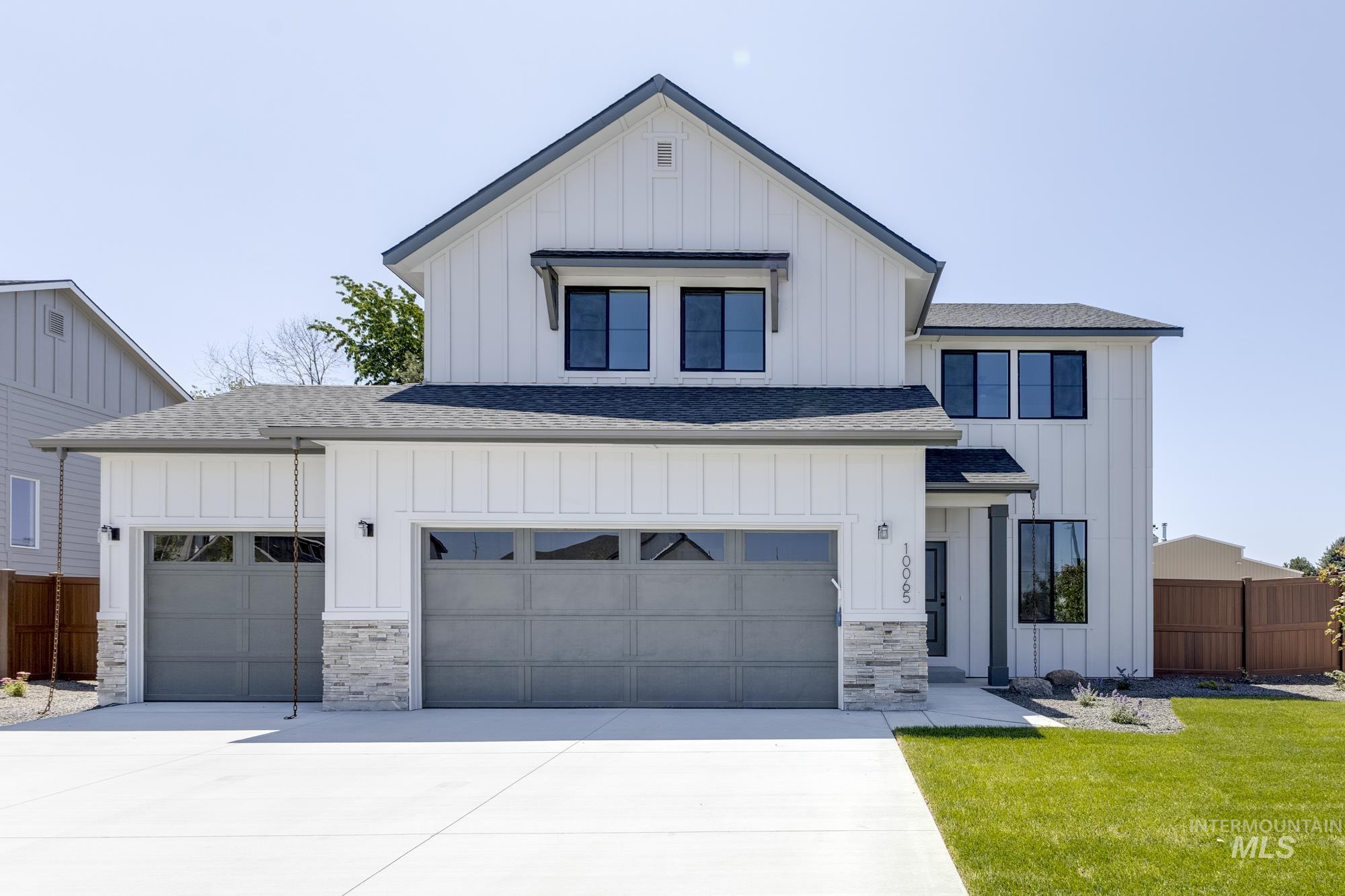 Modern inspired farmhouse featuring a shingled roof, board and batten siding, driveway, and stone siding