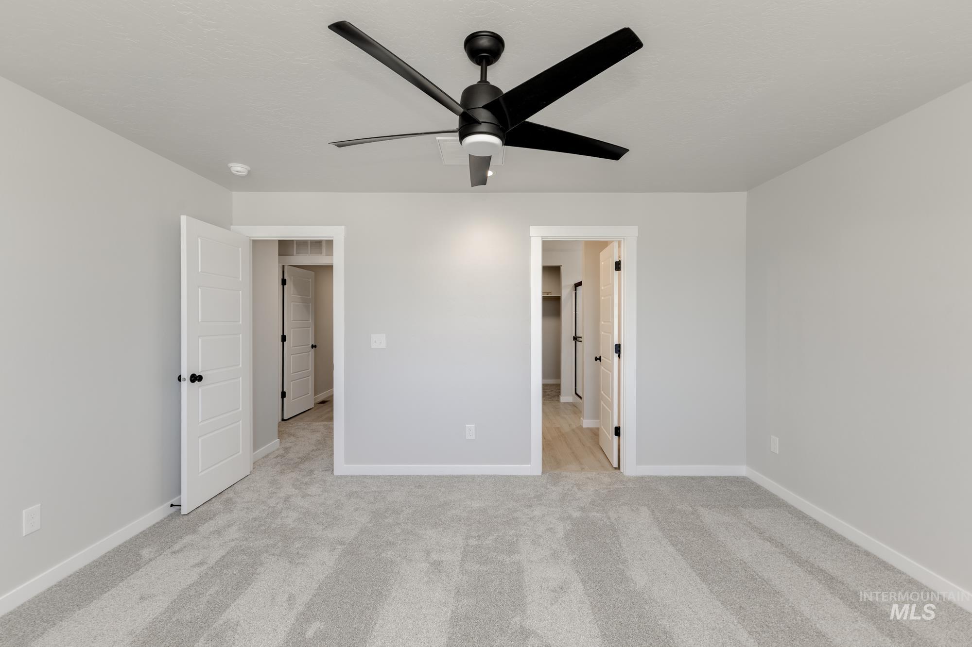 Unfurnished bedroom with light carpet and a ceiling fan