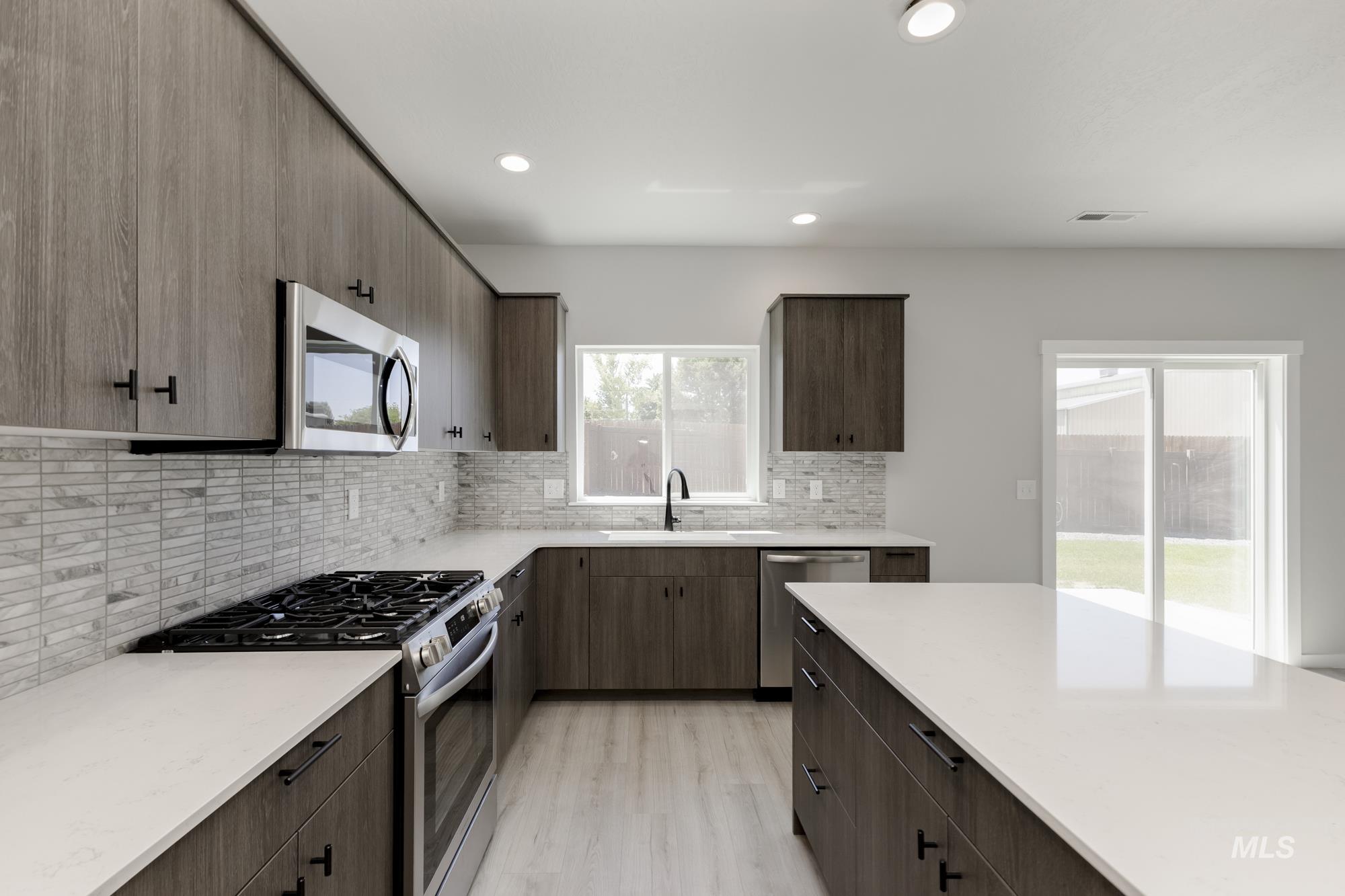 Kitchen with stainless steel appliances, backsplash, light wood-style flooring, recessed lighting, and dark brown cabinetry