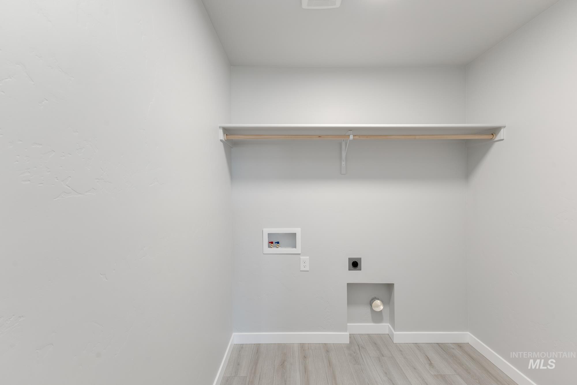 Laundry room with hookup for a washing machine, light wood finished floors, and hookup for an electric dryer