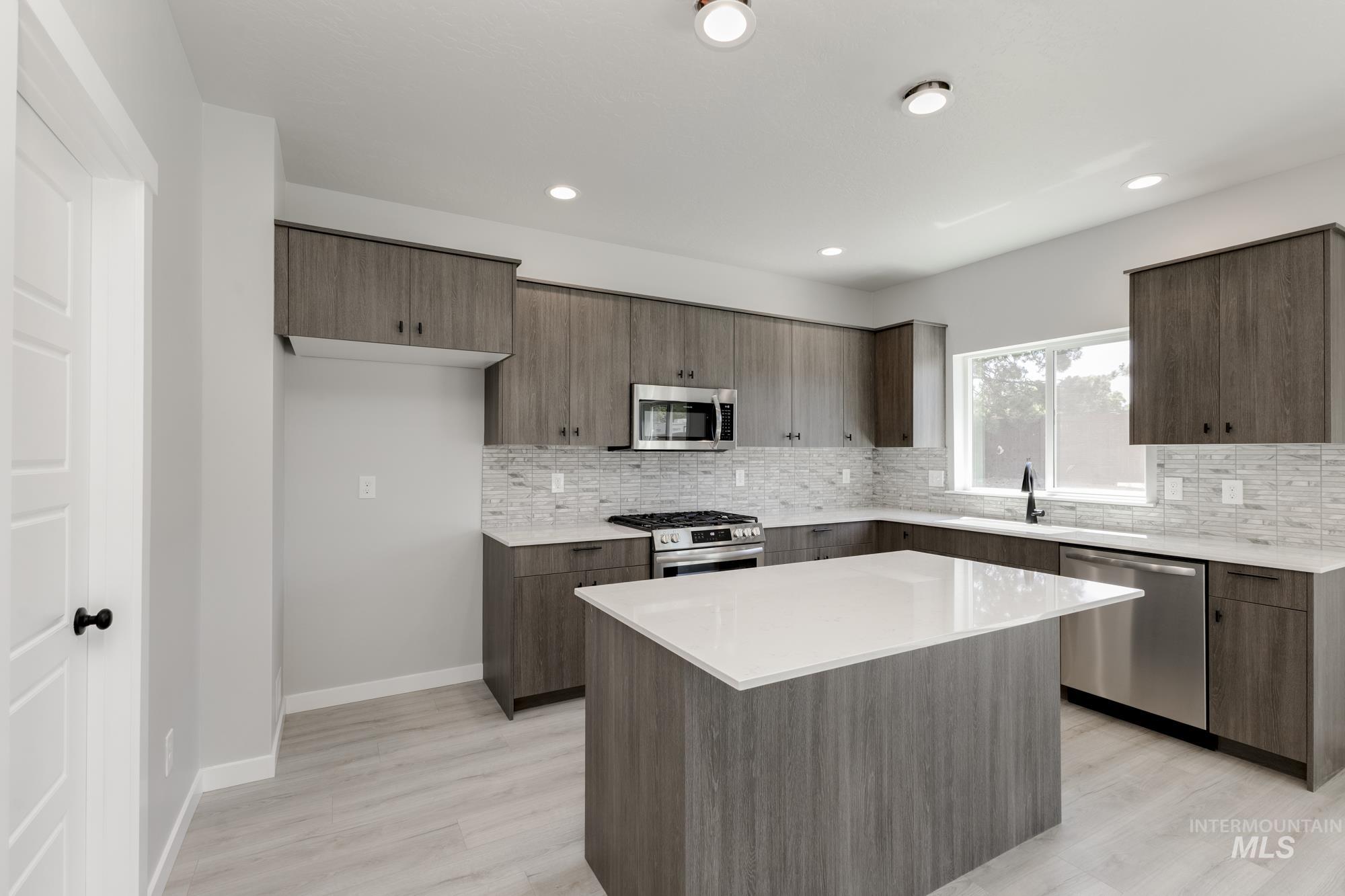 Kitchen with stainless steel appliances, decorative backsplash, light wood-type flooring, and recessed lighting