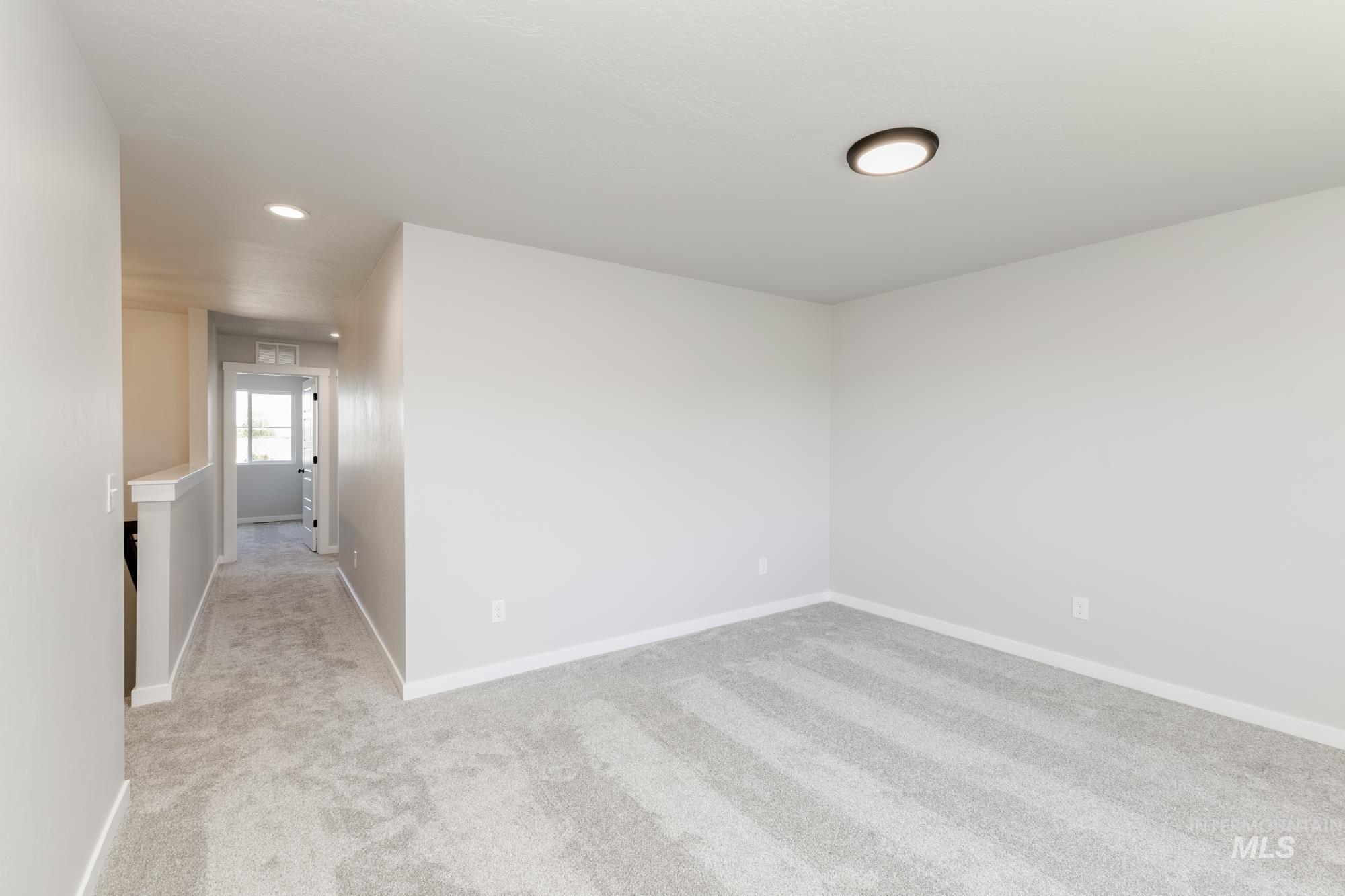 Empty room with light colored carpet and recessed lighting