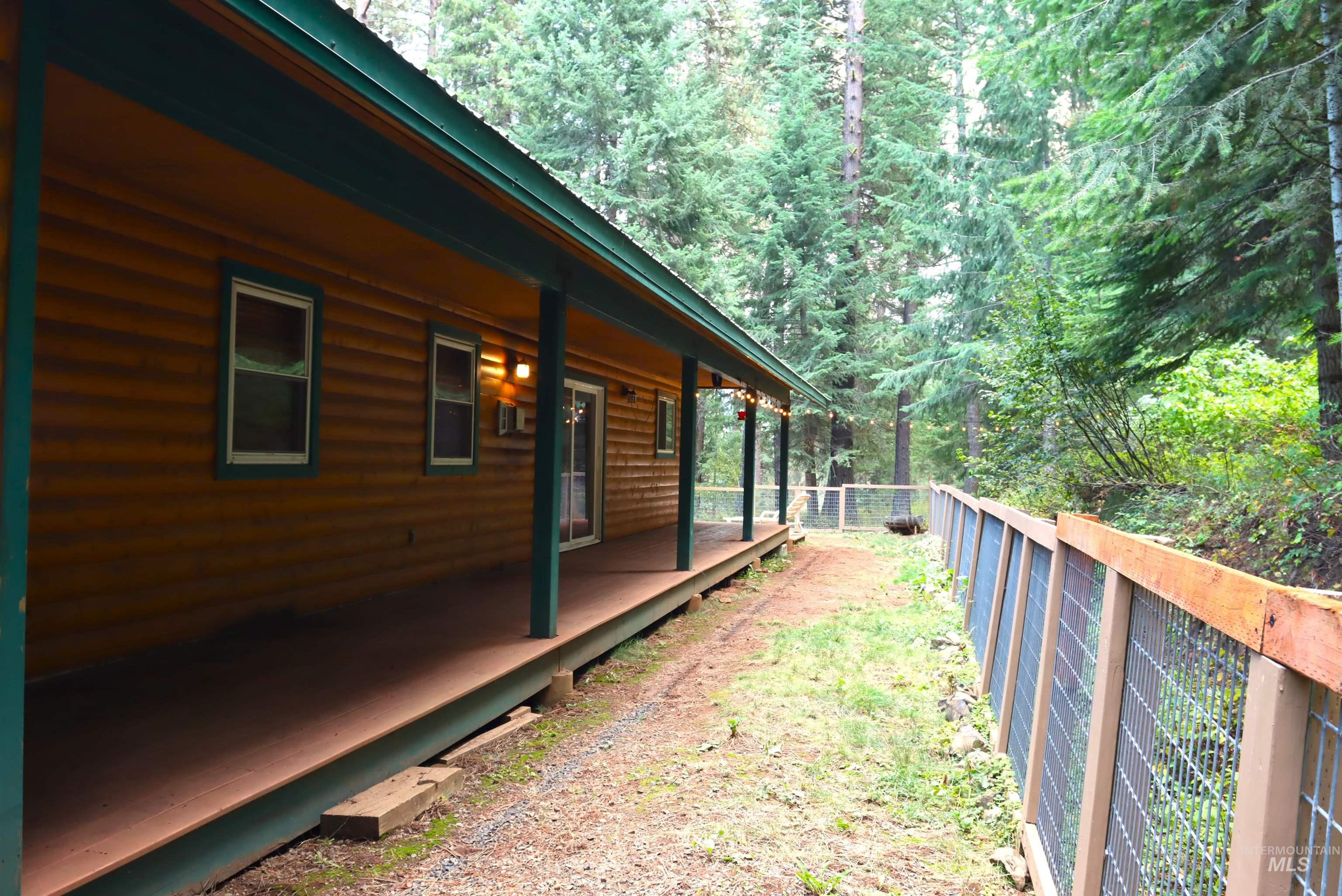View of home's exterior featuring log veneer siding, a fenced backyard, and a forest view