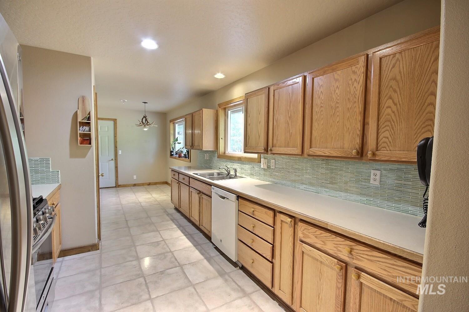 Kitchen with light countertops, tasteful backsplash, stainless steel appliances, hanging light fixtures, and a chandelier