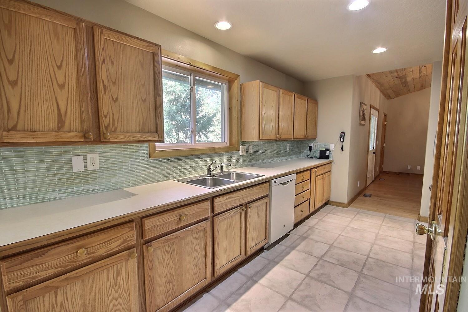 Kitchen featuring tasteful backsplash, light countertops, white dishwasher, and recessed lighting