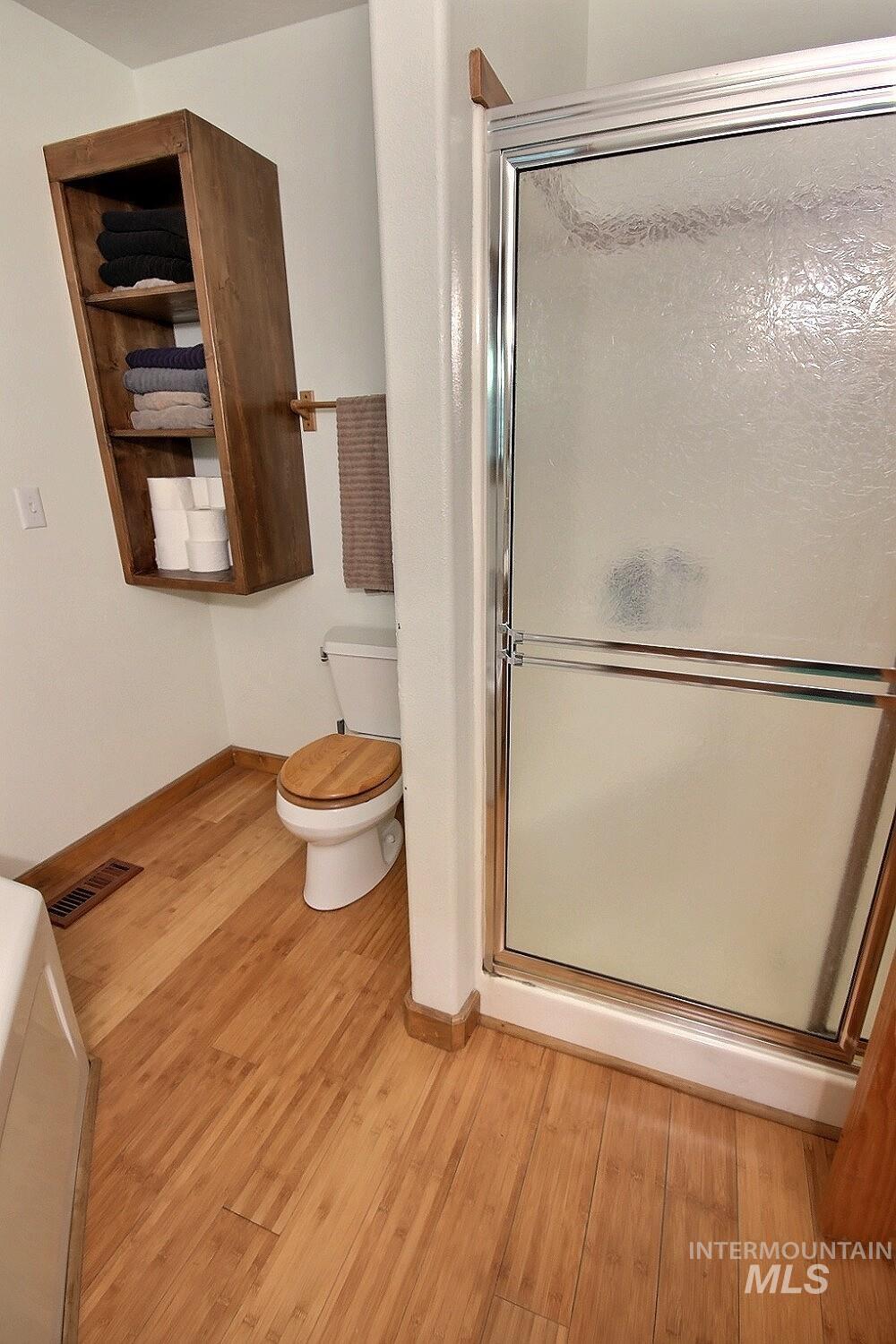 Full bathroom with a stall shower and light wood-style floors