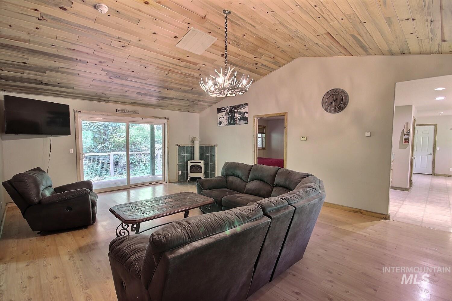 Living room with light wood-style flooring, wooden ceiling, a chandelier, and high vaulted ceiling