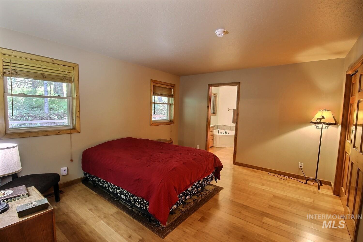 Bedroom with light wood-style floors and ensuite bath