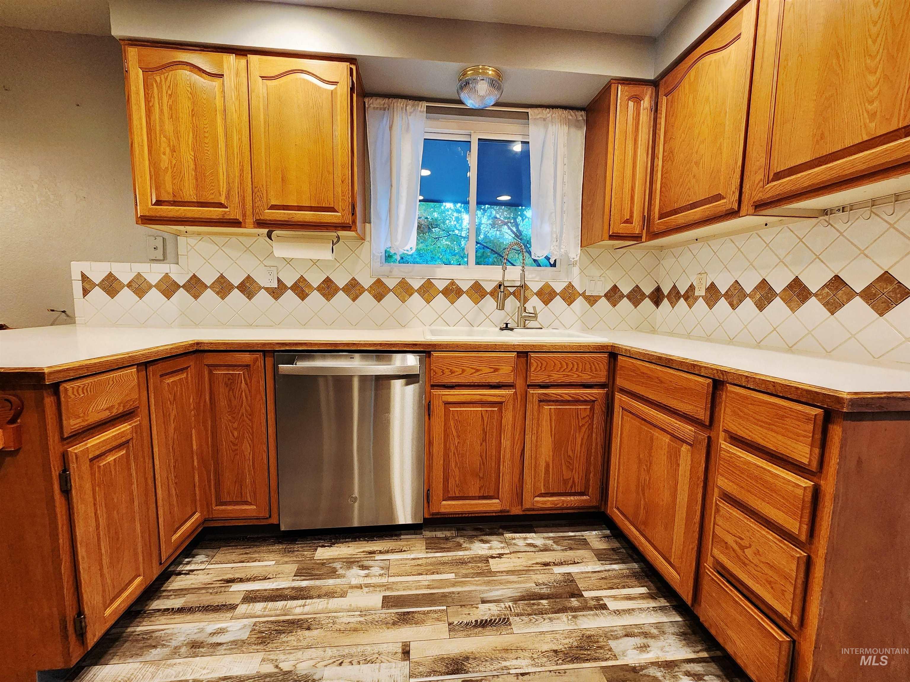 Kitchen with light countertops, dishwasher, brown cabinets, and light wood-style flooring