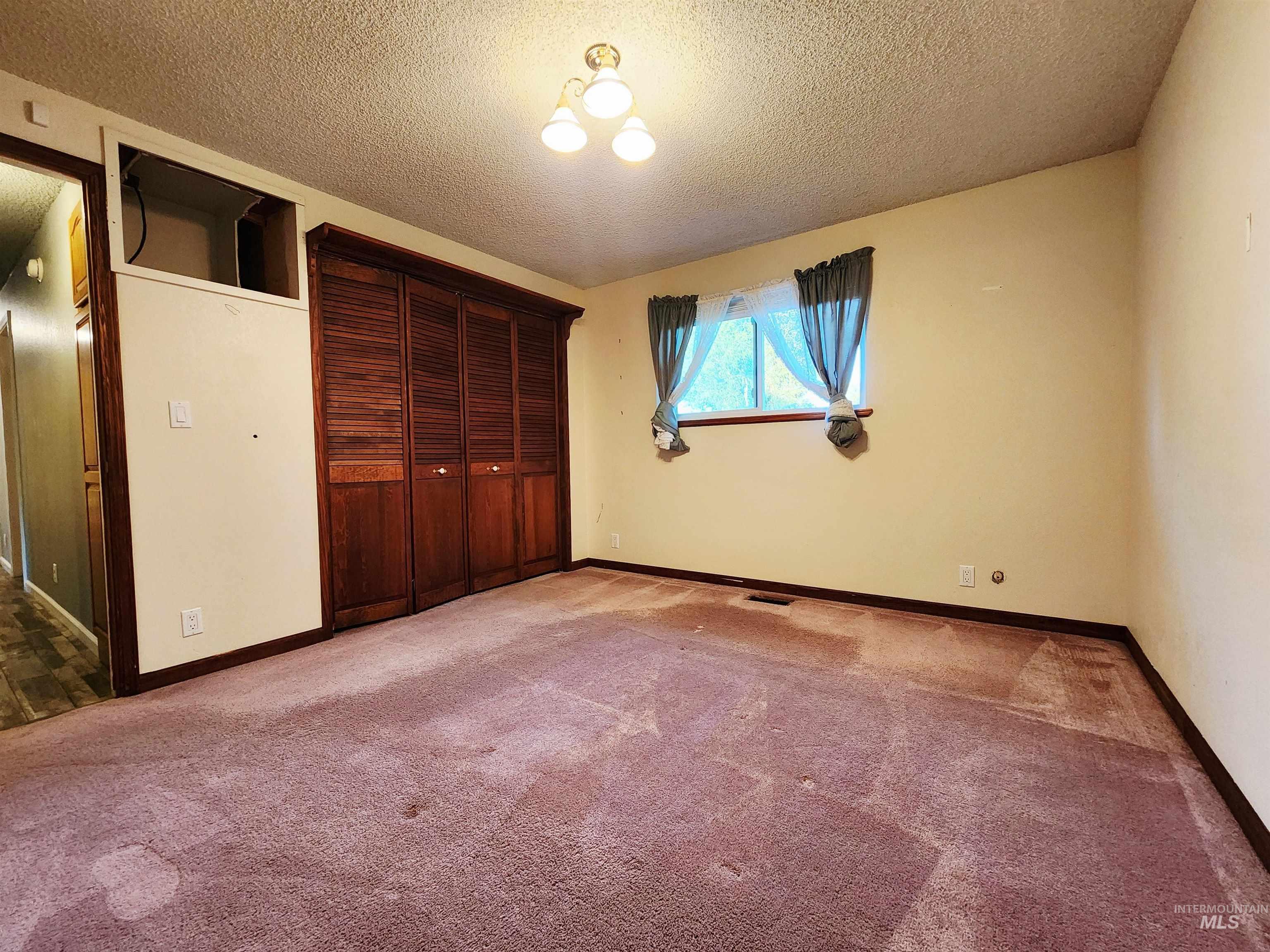 Unfurnished bedroom with carpet flooring, a textured ceiling, and a closet