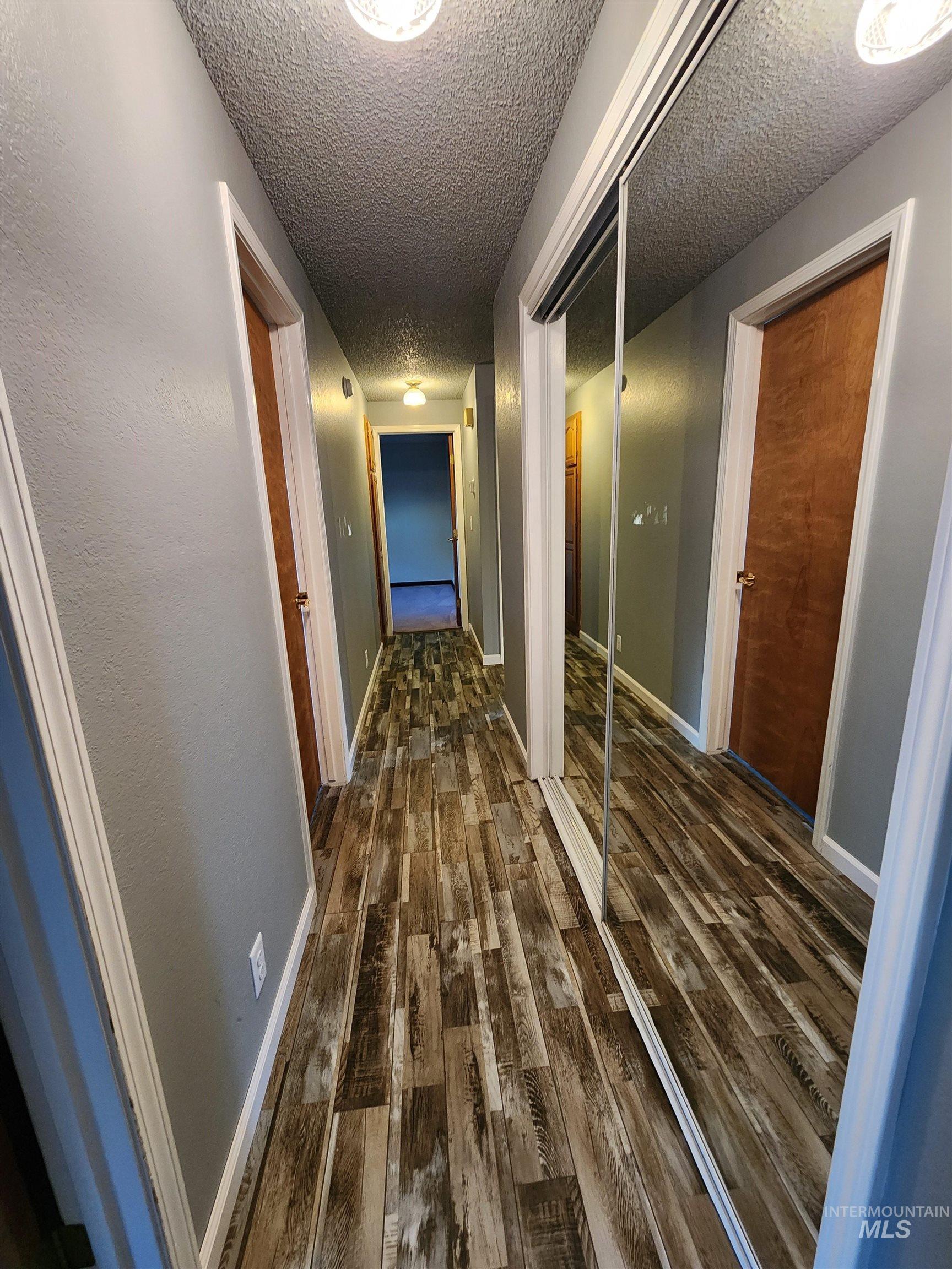 Hallway with dark wood finished floors and a textured ceiling