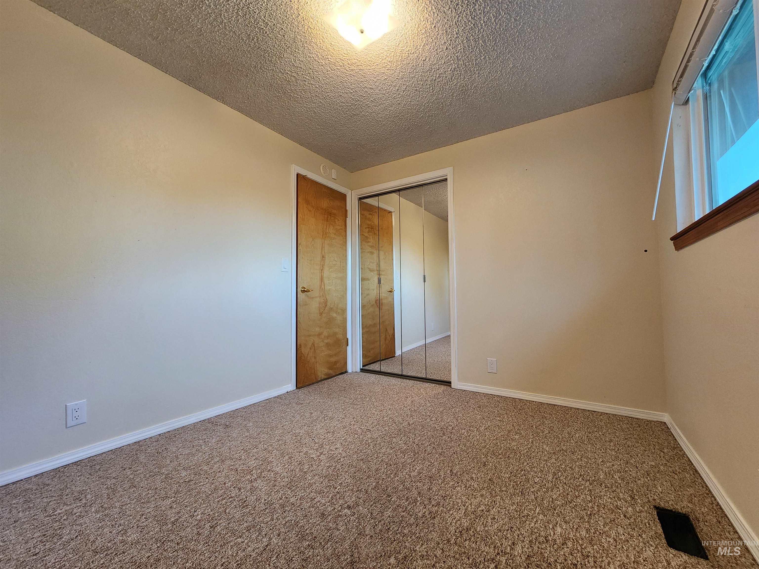 Unfurnished bedroom featuring carpet, a textured ceiling, and a closet