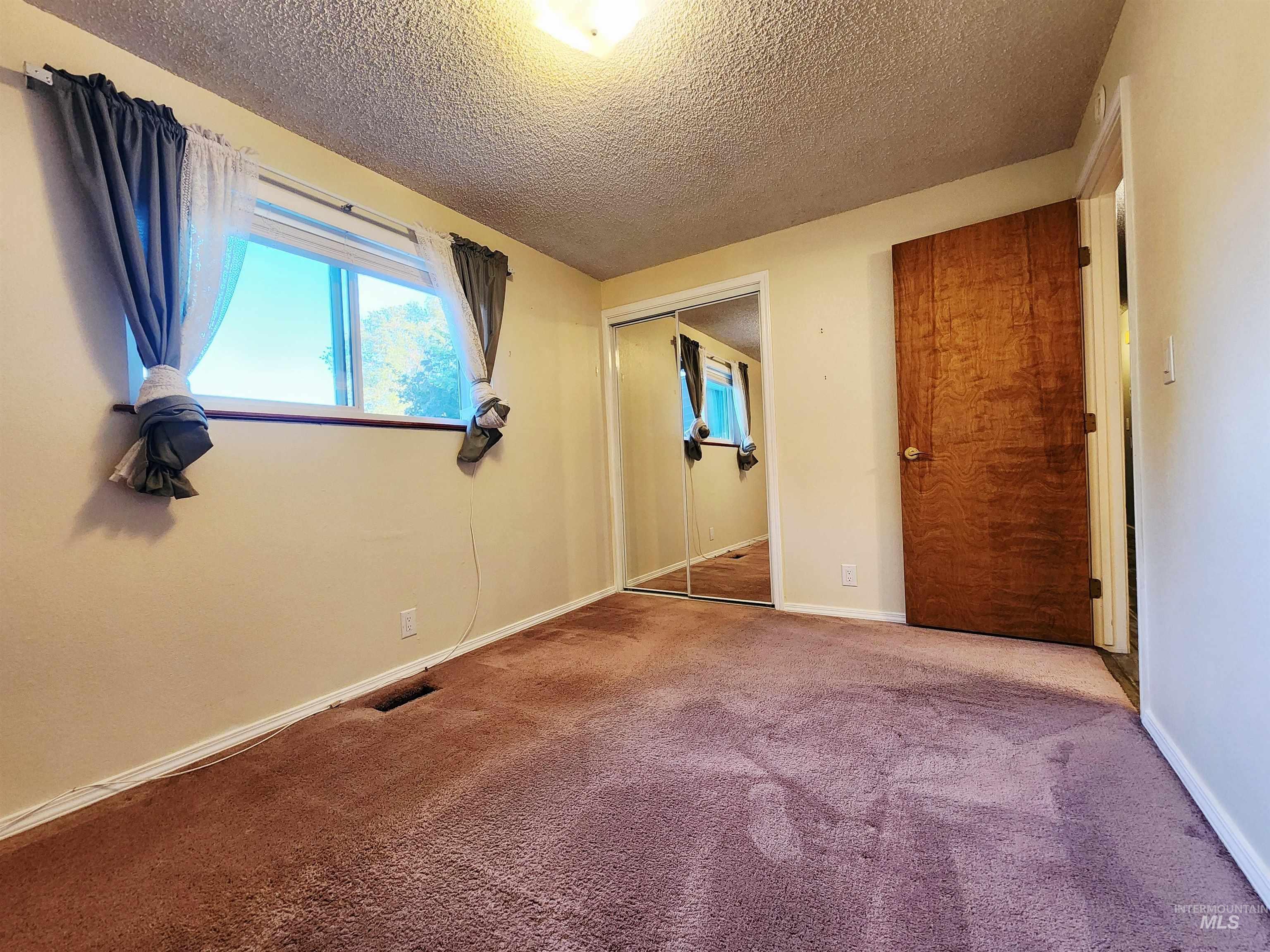 Unfurnished bedroom with a textured ceiling, carpet, and a closet