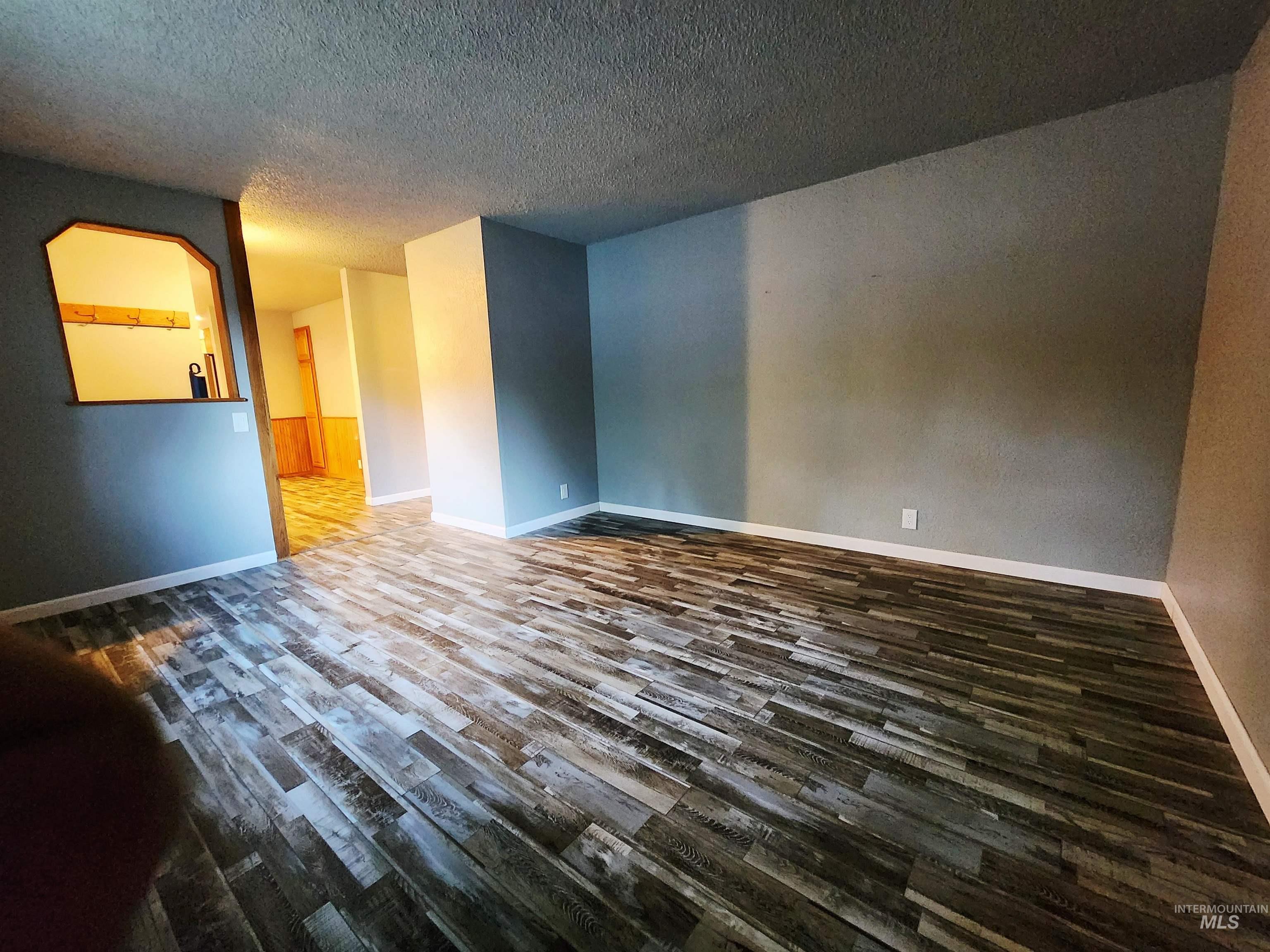 Unfurnished room featuring dark wood-style flooring and a textured ceiling